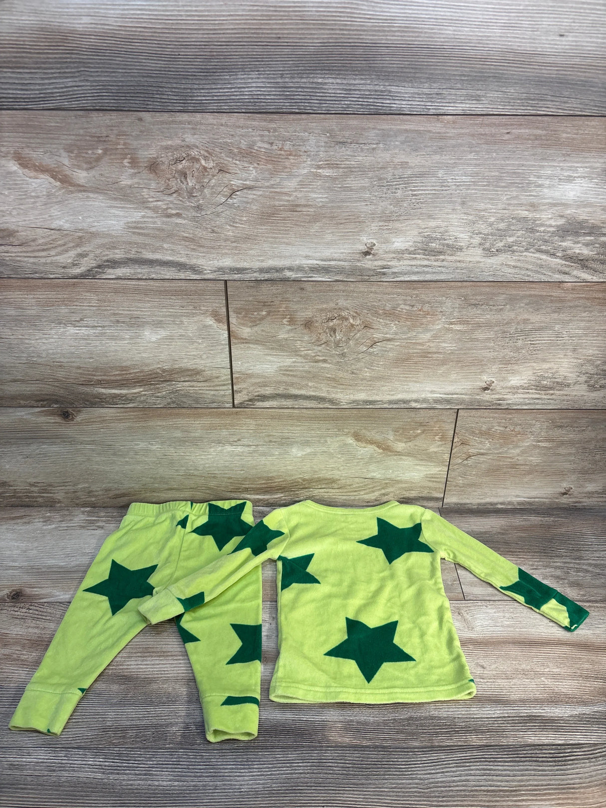 Kids green pajama set with dark green star print, long sleeve top and pants, laid flat