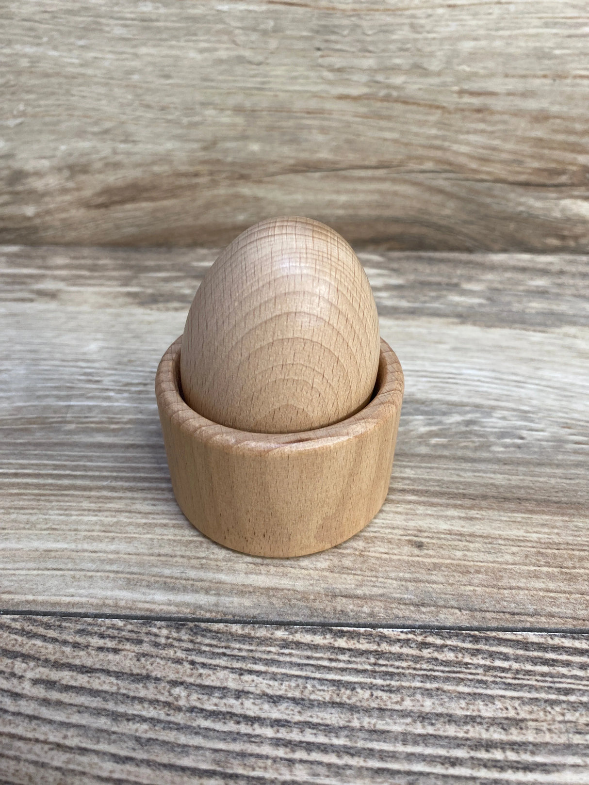 Natural wood egg and cup toy on a wooden surface, Montessori sensory learning material