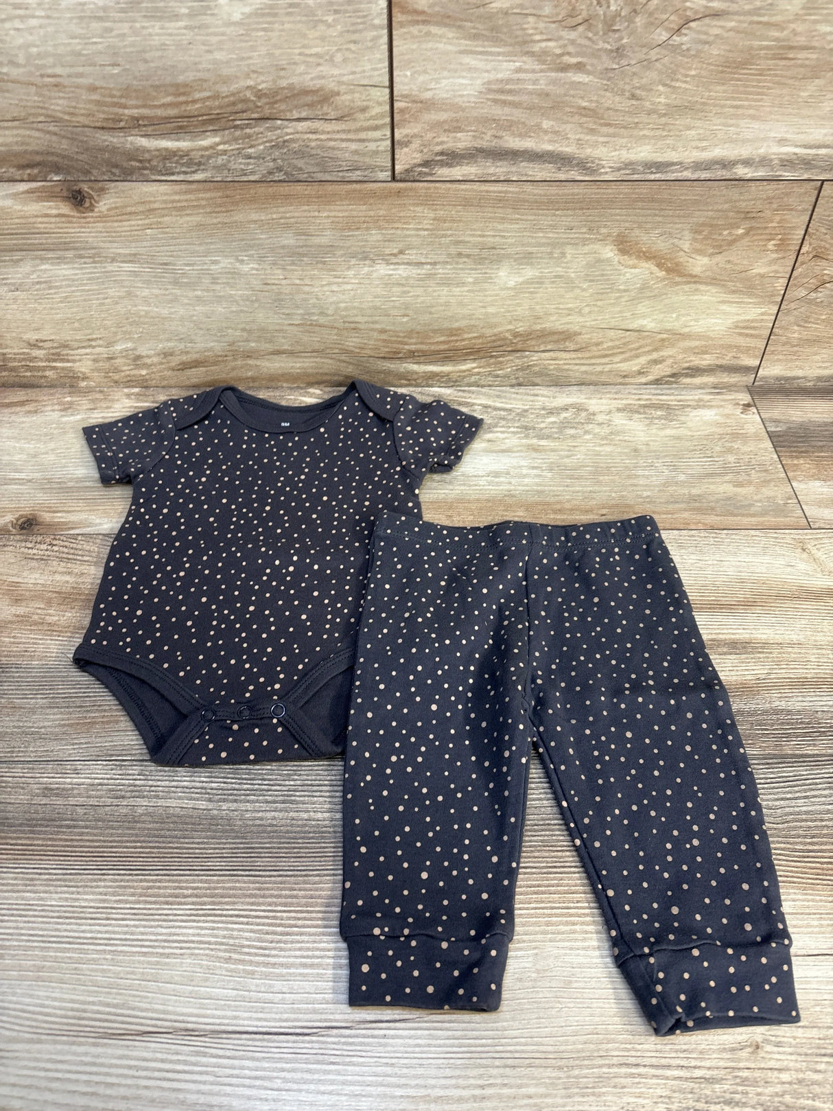Front view of 2-piece grey polka dot bodysuit and pants set showcasing beige dots on 100% cotton with wood floor background