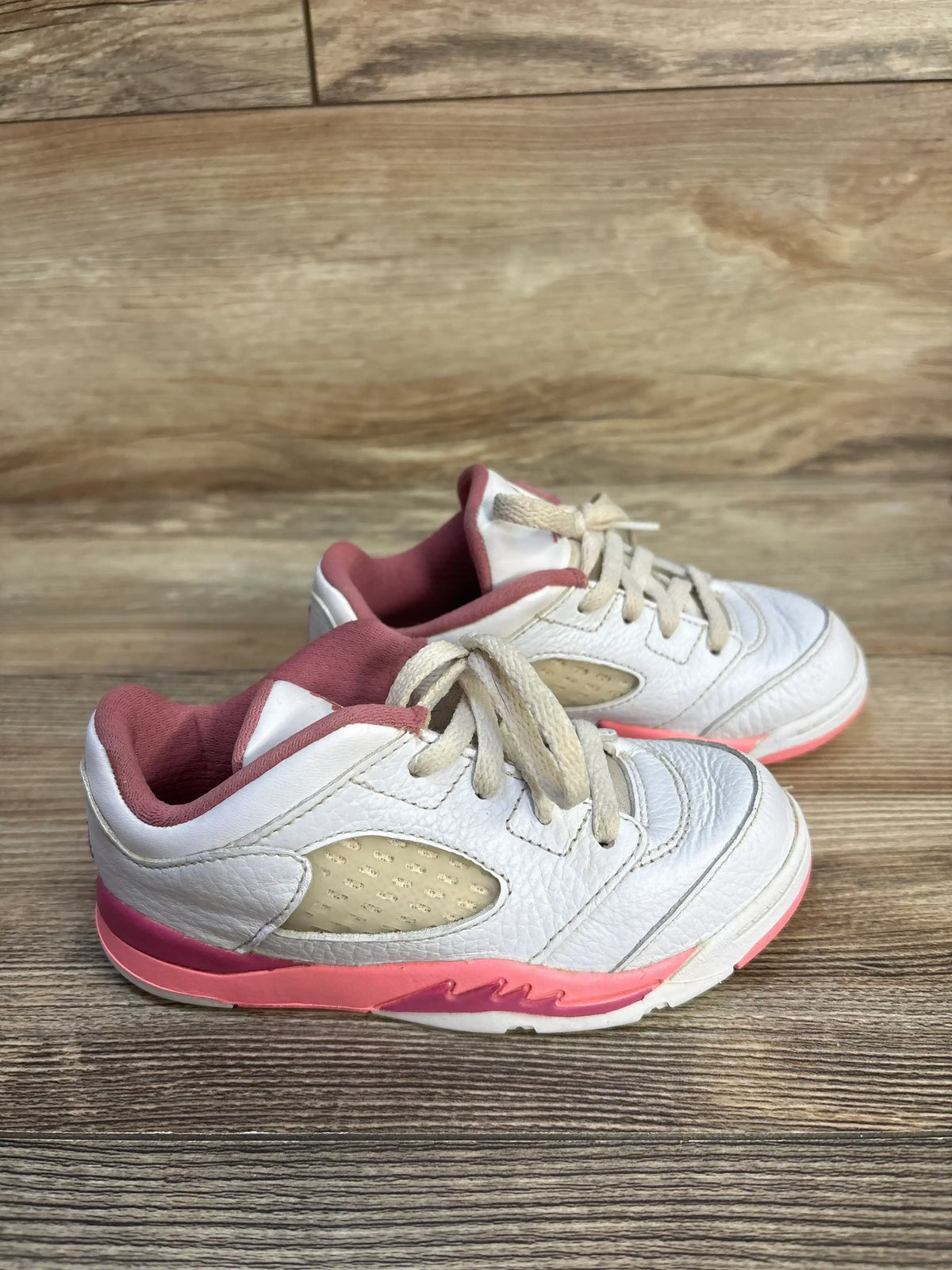 Three-quarter view of Air Jordan 5 Retro Low TD Crafted For Her Sneakers size 9c in white leather with pink accents and laces on wood plank floor
