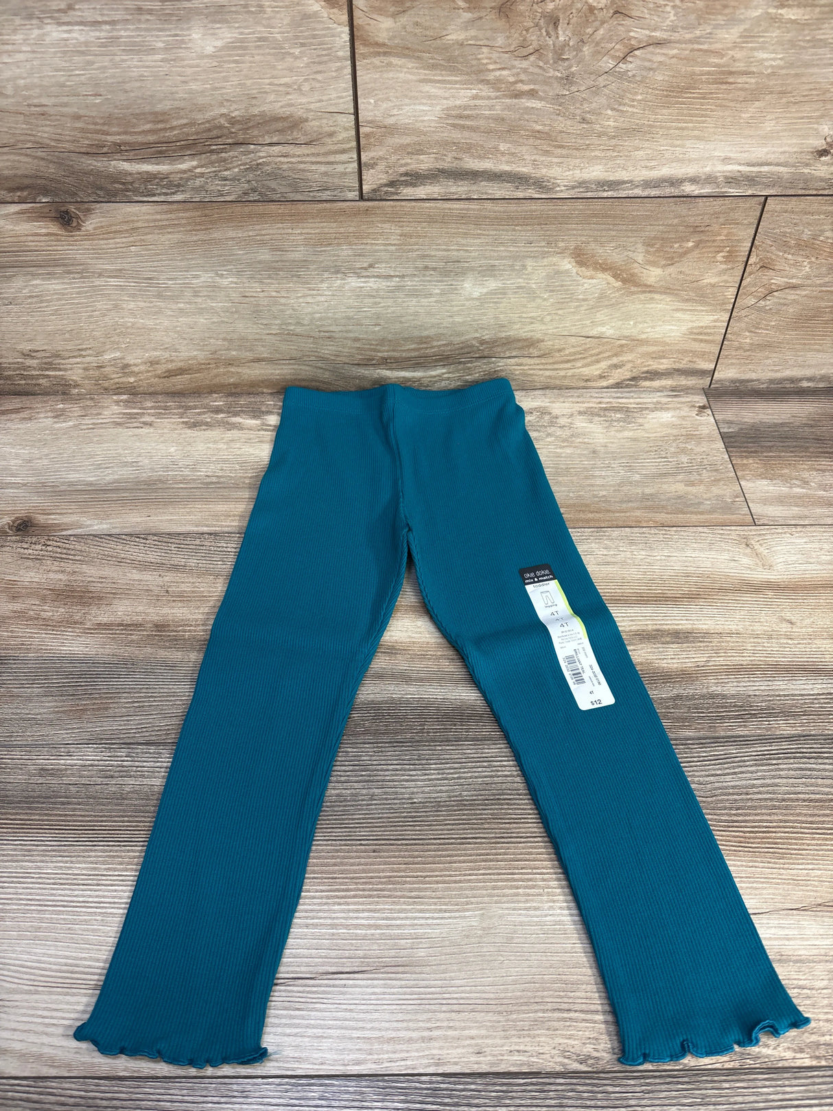 Teal ribbed toddler leggings size 4T with wavy hem detail on wooden floor