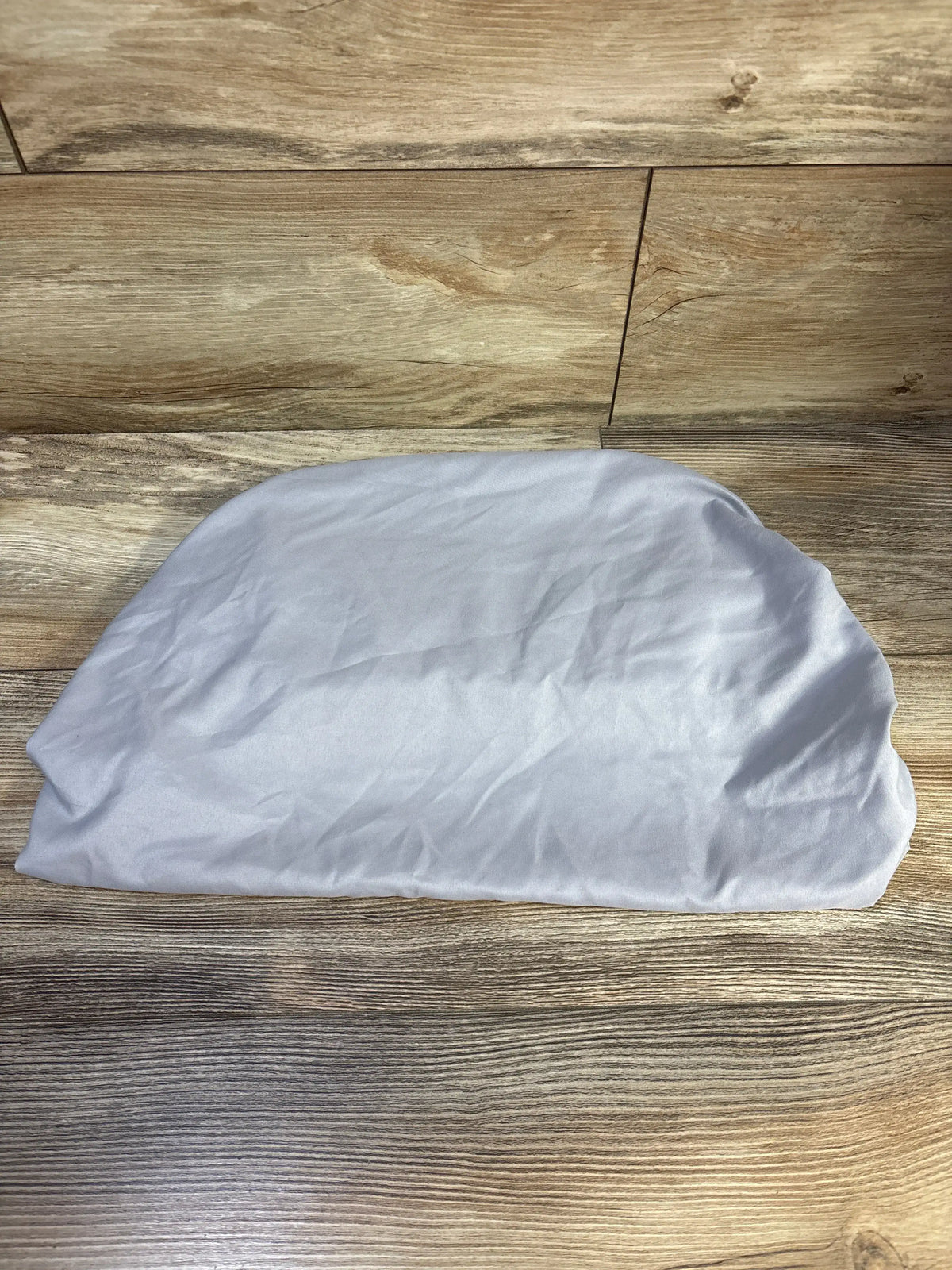 Top view of Parent’s Choice fitted bassinet sheet showcasing its grey fitted design on a wood-grain floor