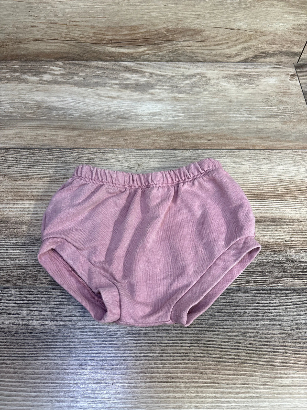Front view of Cat & Jack pink bloomers showcasing elastic waistband and leg openings on a wood-grain surface