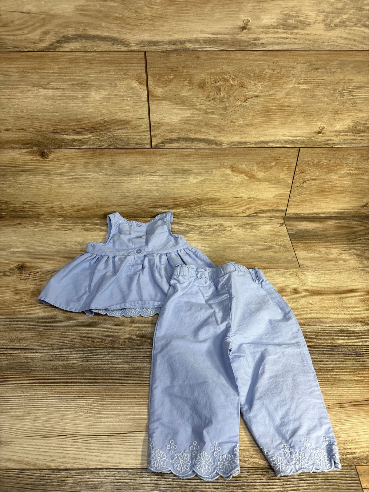 Front view of Tahari Baby two-piece blue set showcasing embroidered details and scalloped hems on a wood floor