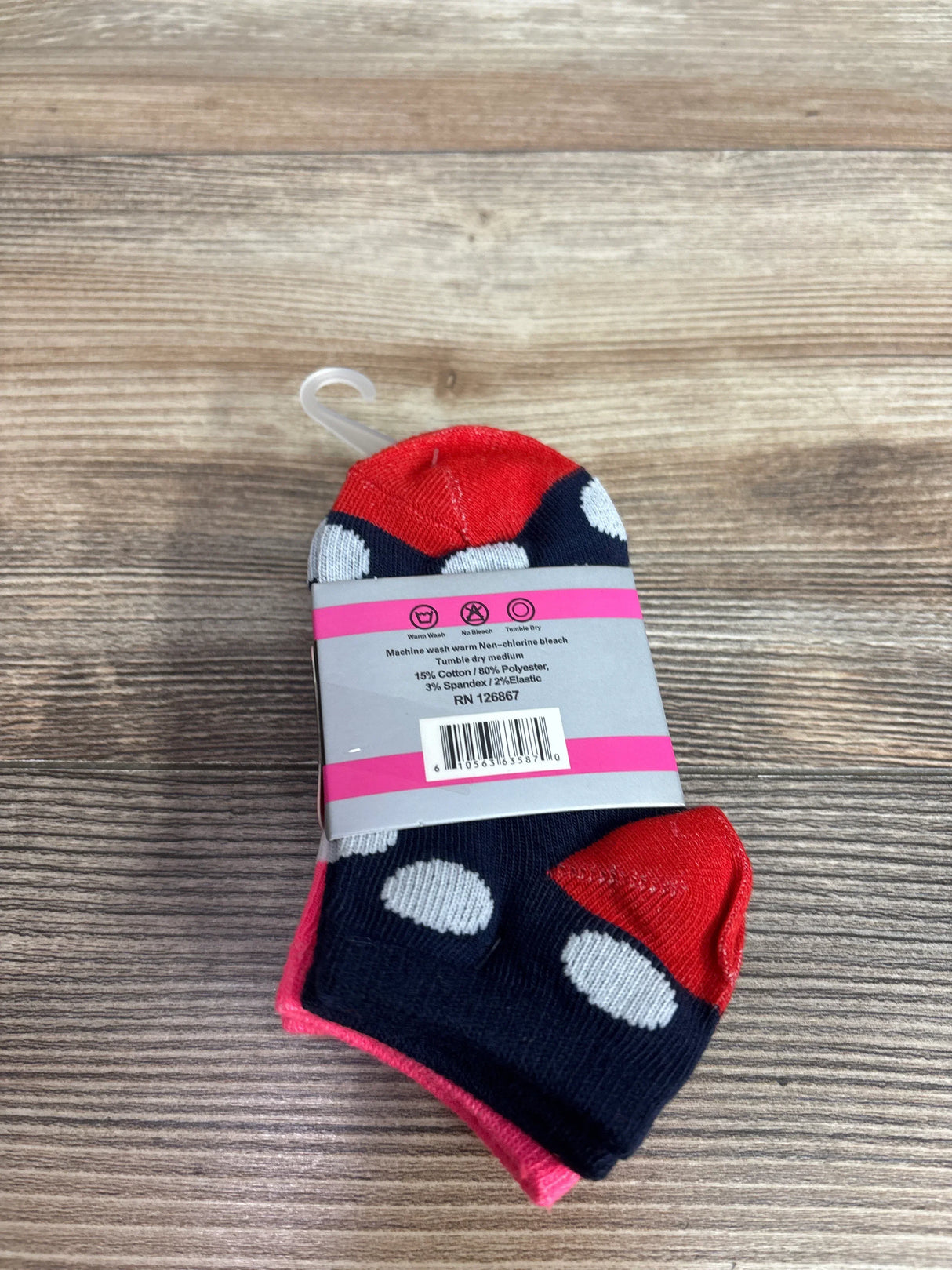 Bundled view of NEW Step Up socks showing navy blue fabric, white polka dots, and red accents on wood grain
