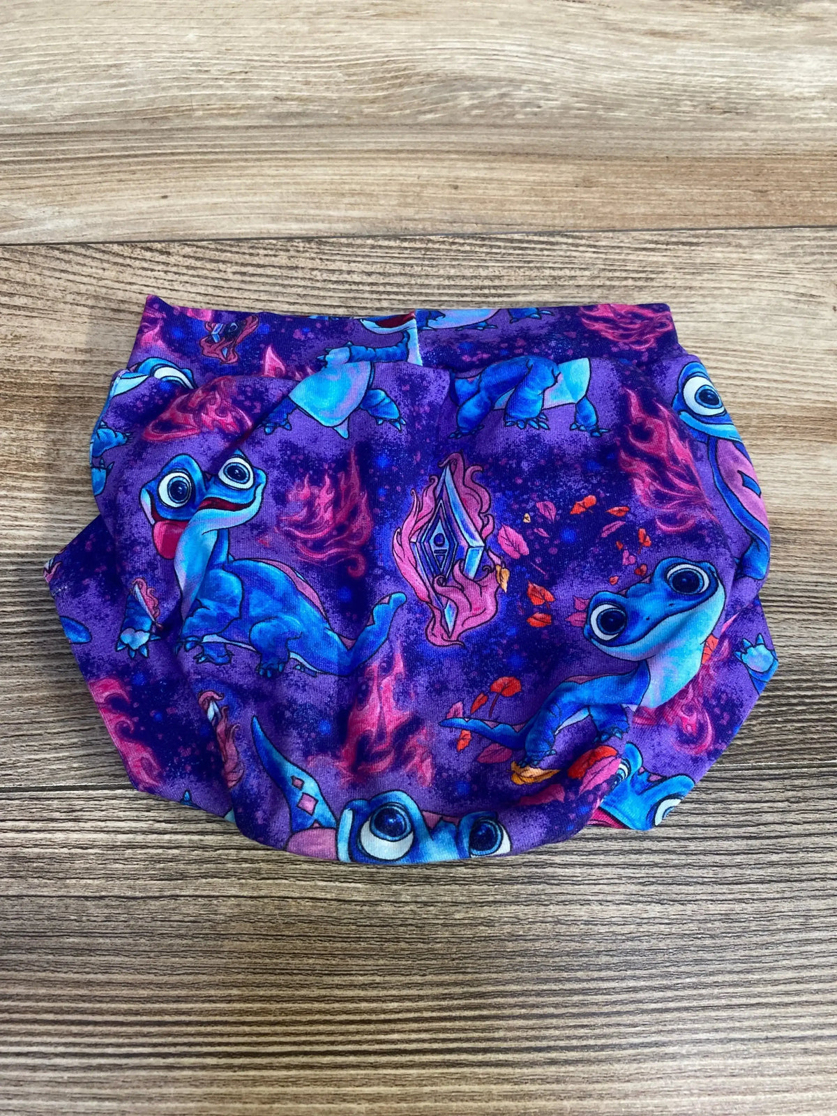 Flat lay of Handmade Disney Frozen Bruni Bloomer Purple sz 3-6m showcasing Bruni print on wood-grain background