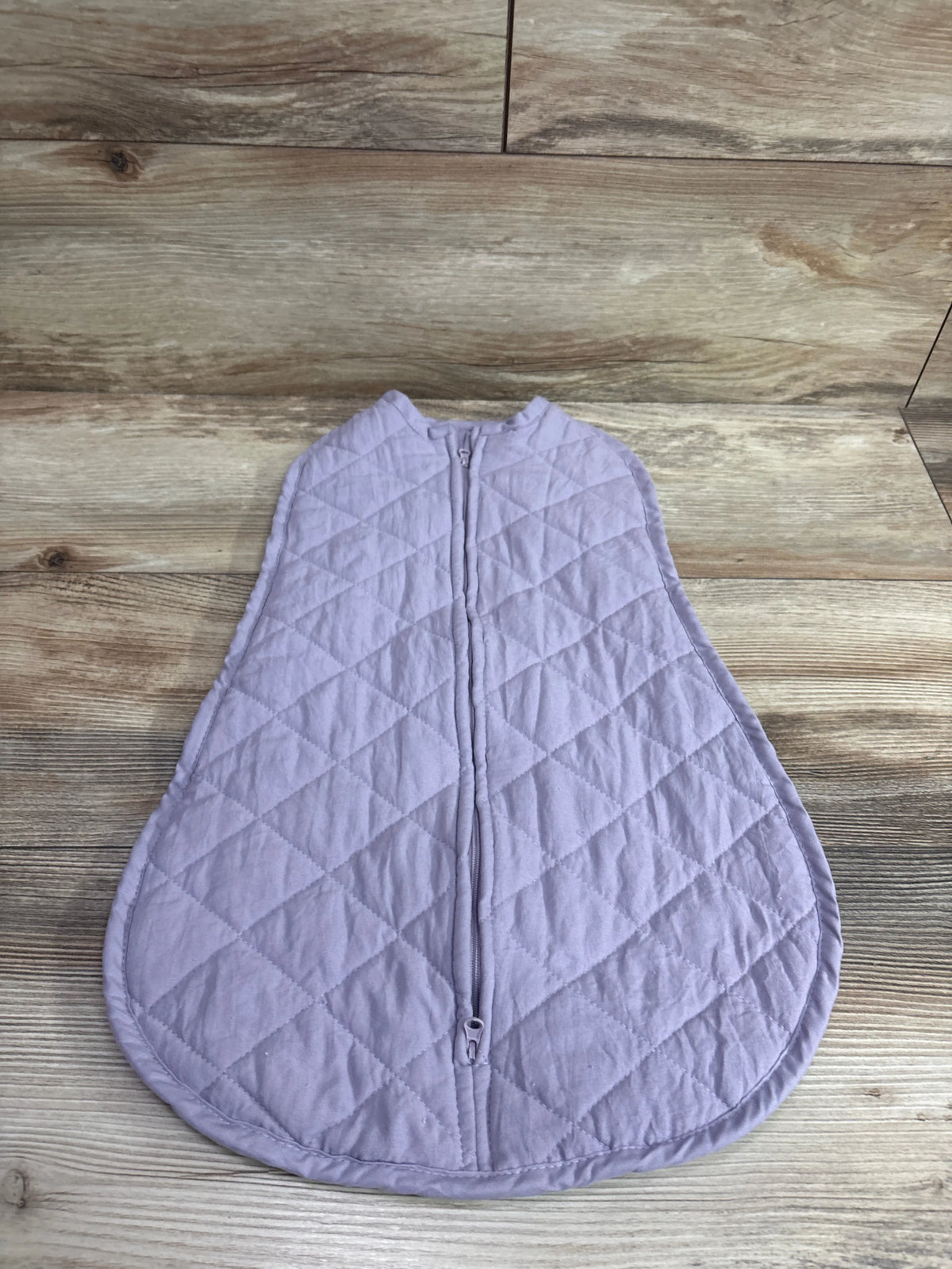 Purple quilted wearable blanket swaddle for infants size 0-6m on a wood floor