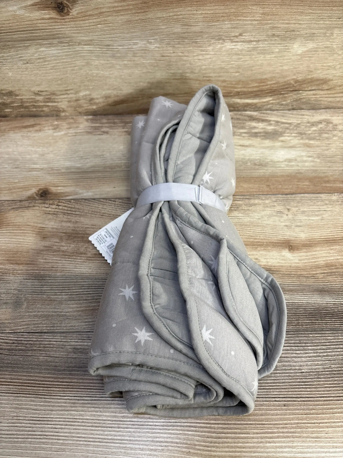 Top-down view of folded grey Cloud Island bamboo jersey quilted baby blanket showing white star print on a wood background