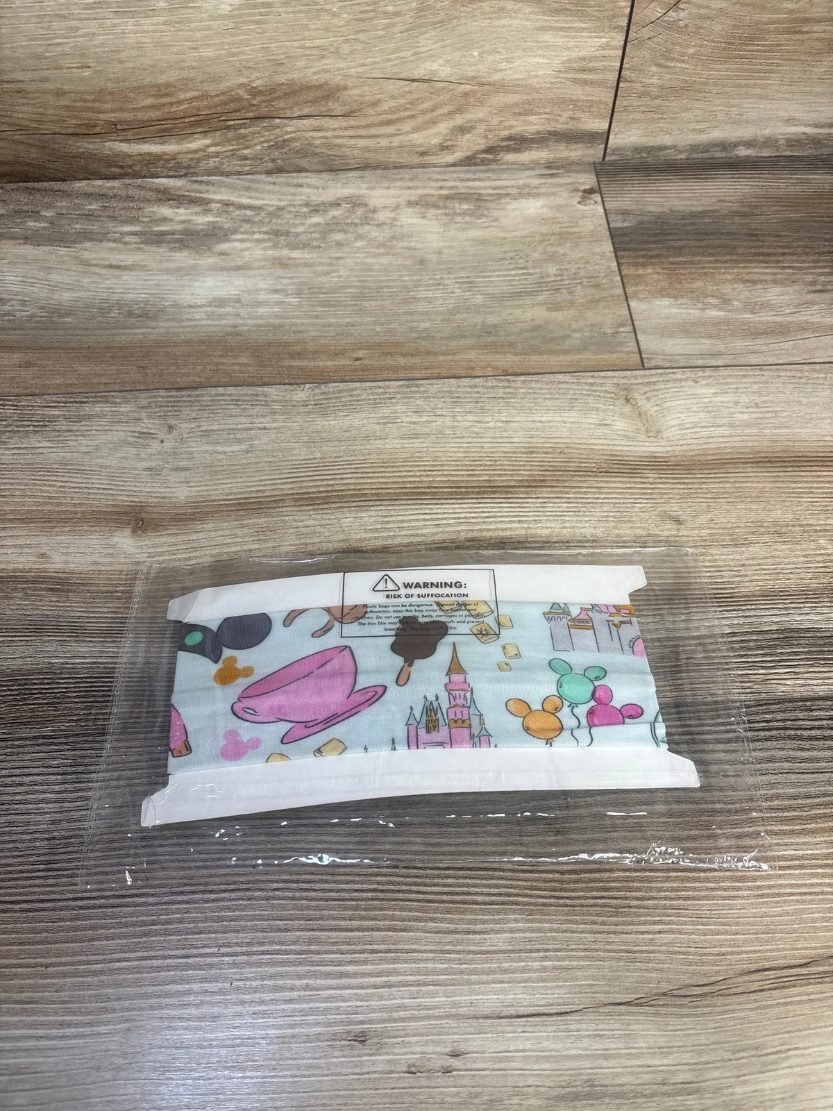Front view of Disney Park theme bow headwrap showcasing attached bow, bamboo material, and stretchy fit in clear packaging