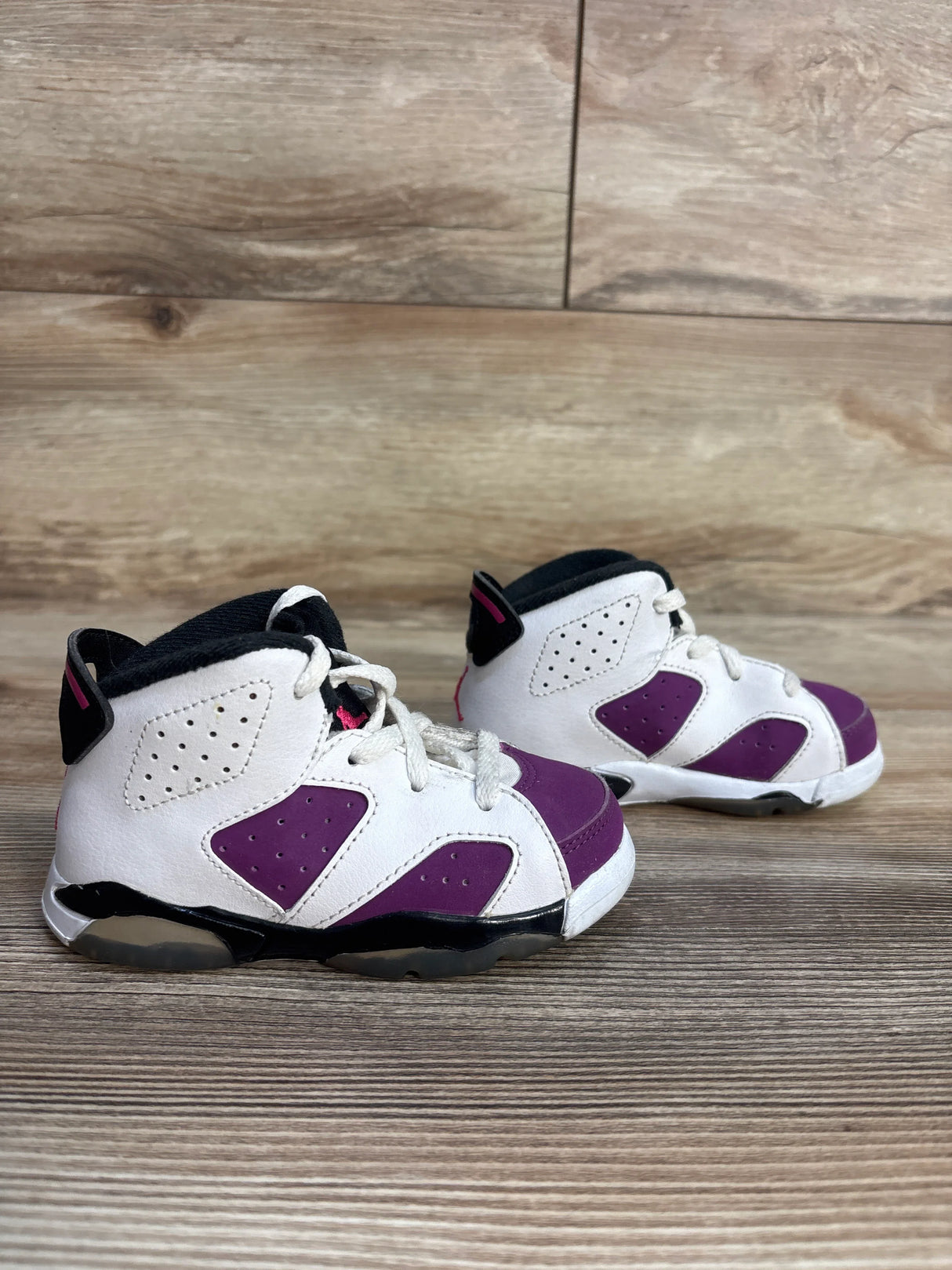 Pair of toddler white and purple sneakers on wooden floor