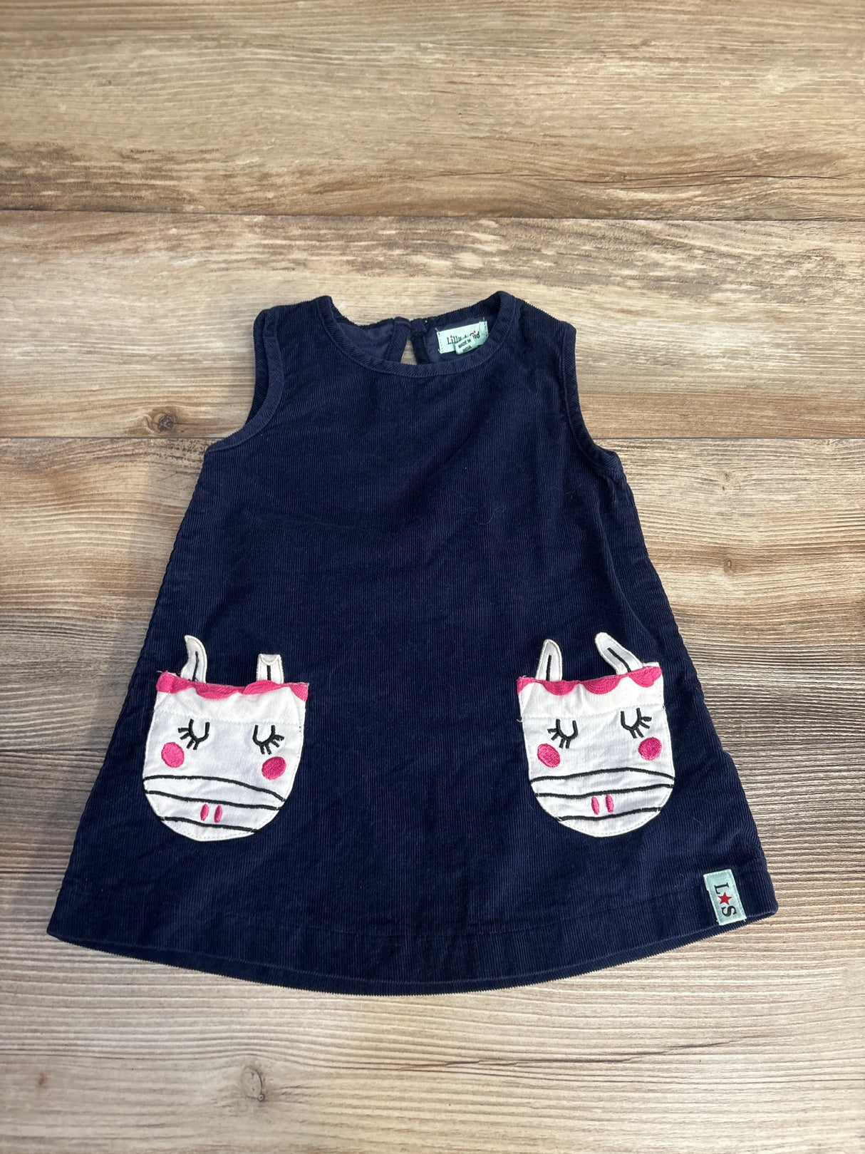 Navy blue toddler dress with cute animal face pockets on wood background