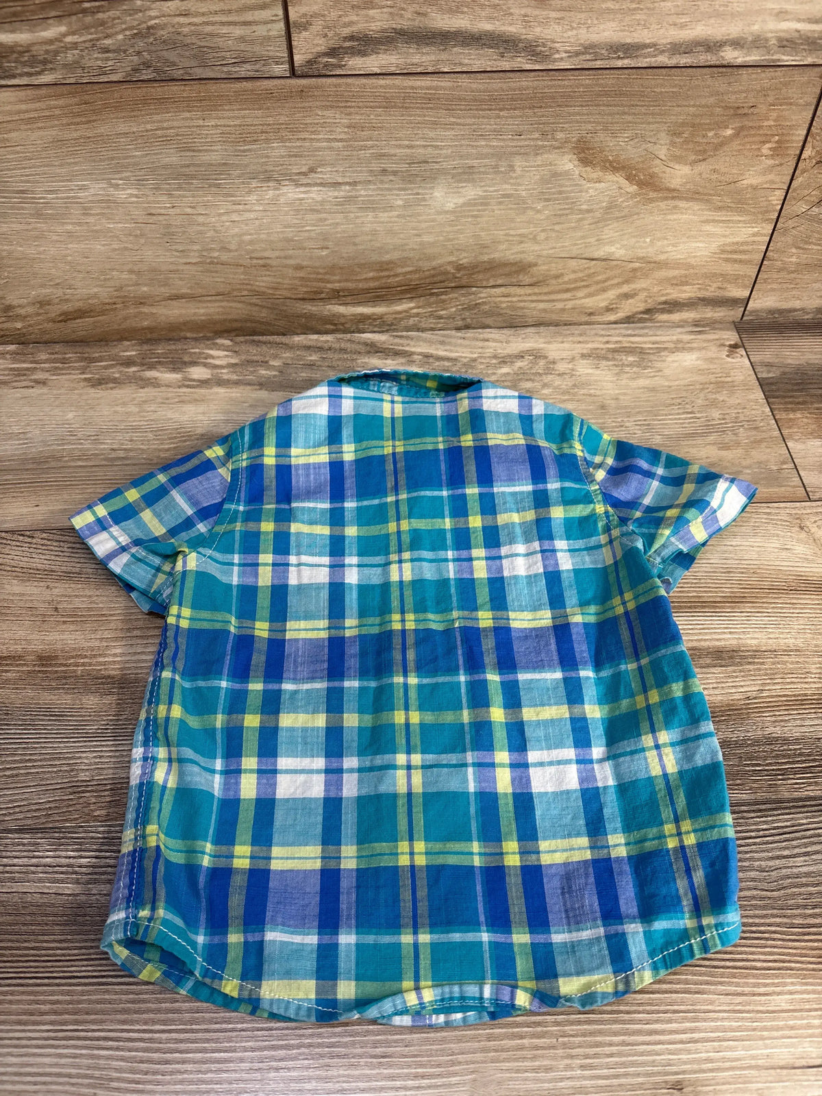 Back view of Cat & Jack blue button-up shirt showcasing plaid pattern with a wood-grain background