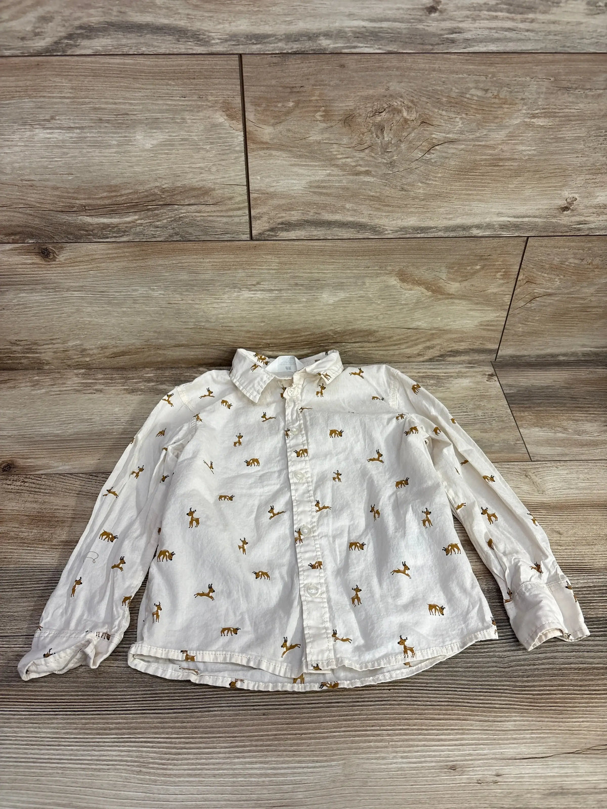 White long-sleeve kids shirt with brown deer print, button-front, laid on wood floor