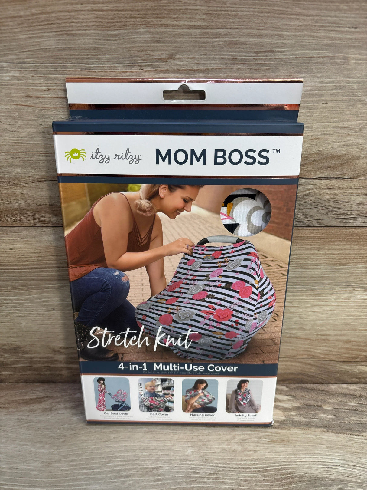 Front view of Itzy Ritzy Mom Boss 4-in-1 cover showing floral-stripes stretch-knit fabric and MOM BOSS text on wood