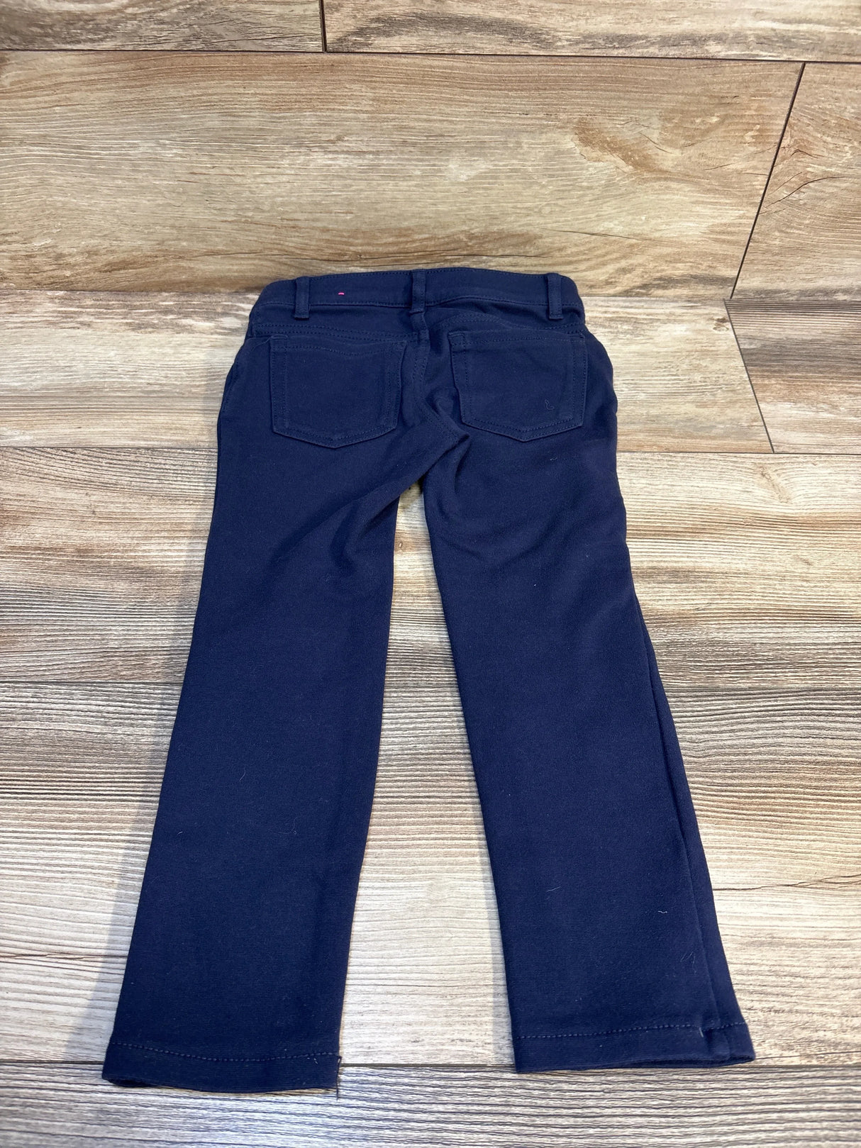 Back view of Children's Place ponte knit pull-on jeggings in tidal navy, size 5T, showing back pockets on wood floor
