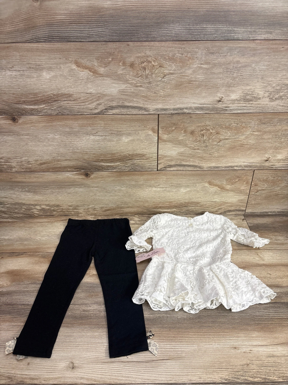 Girls lace white dress with long sleeves and black leggings with bows, displayed on wood floor