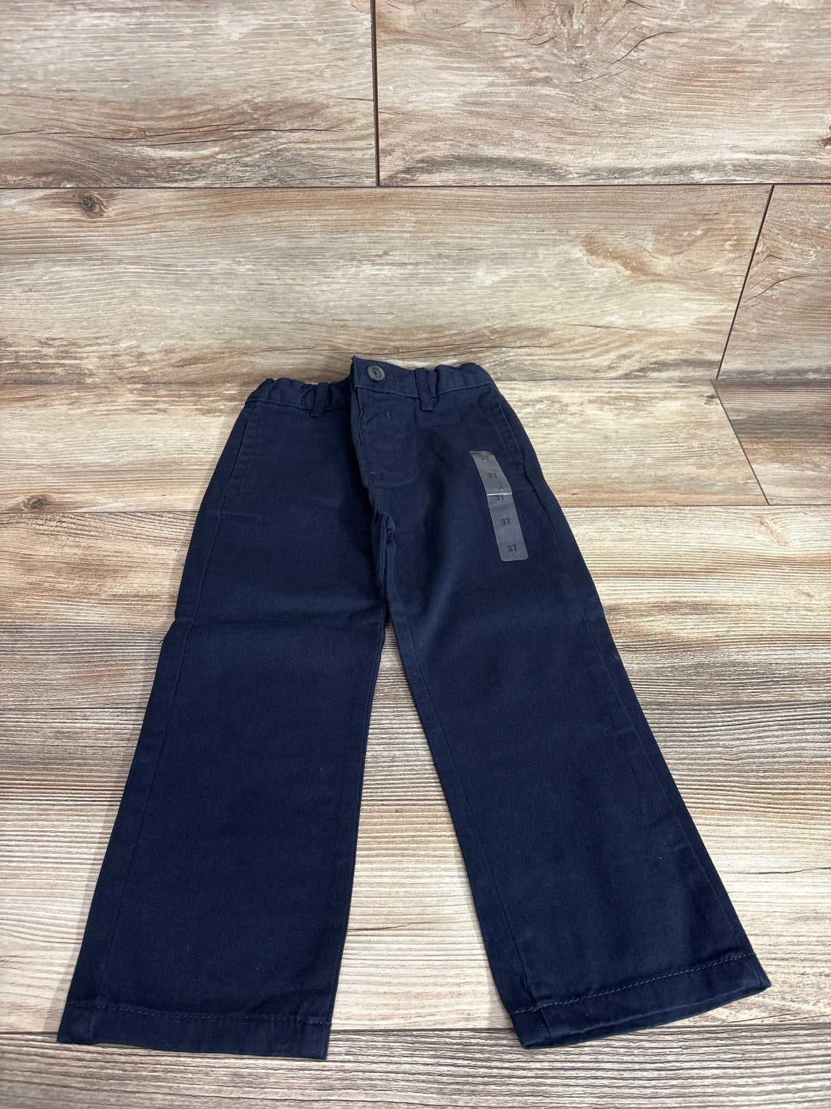 Front view of Children's Place navy toddler chino pants showcasing elasticized waistband and 3T size sticker on wood background