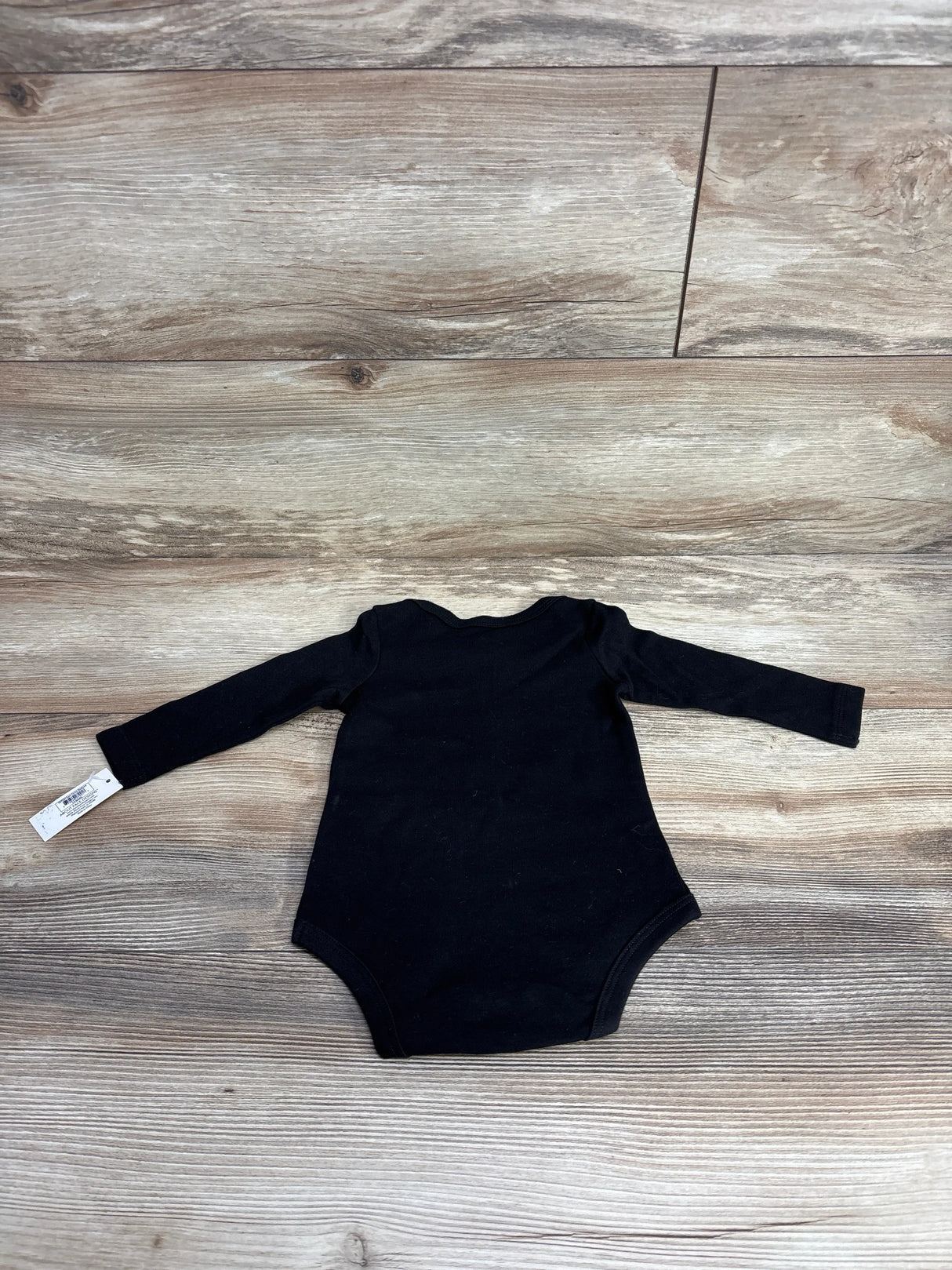 Black long sleeve baby bodysuit on wood background, gently used kids clothing