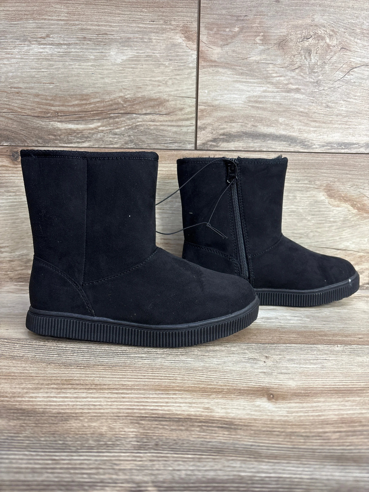 Black suede kids ankle boots with side zipper on wood background