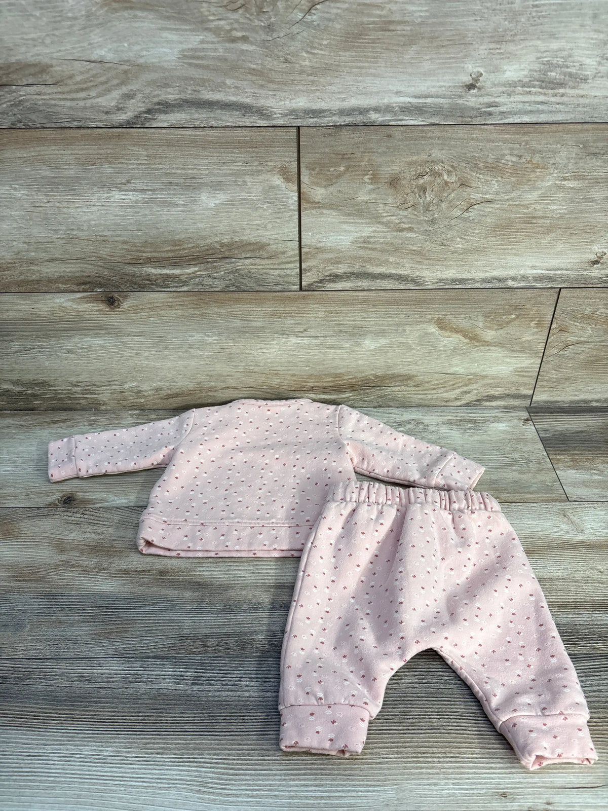 Flat lay of Nordstrom two-piece floral sweatshirt and pants set in pink, showcasing the matching pattern on a wood-look background