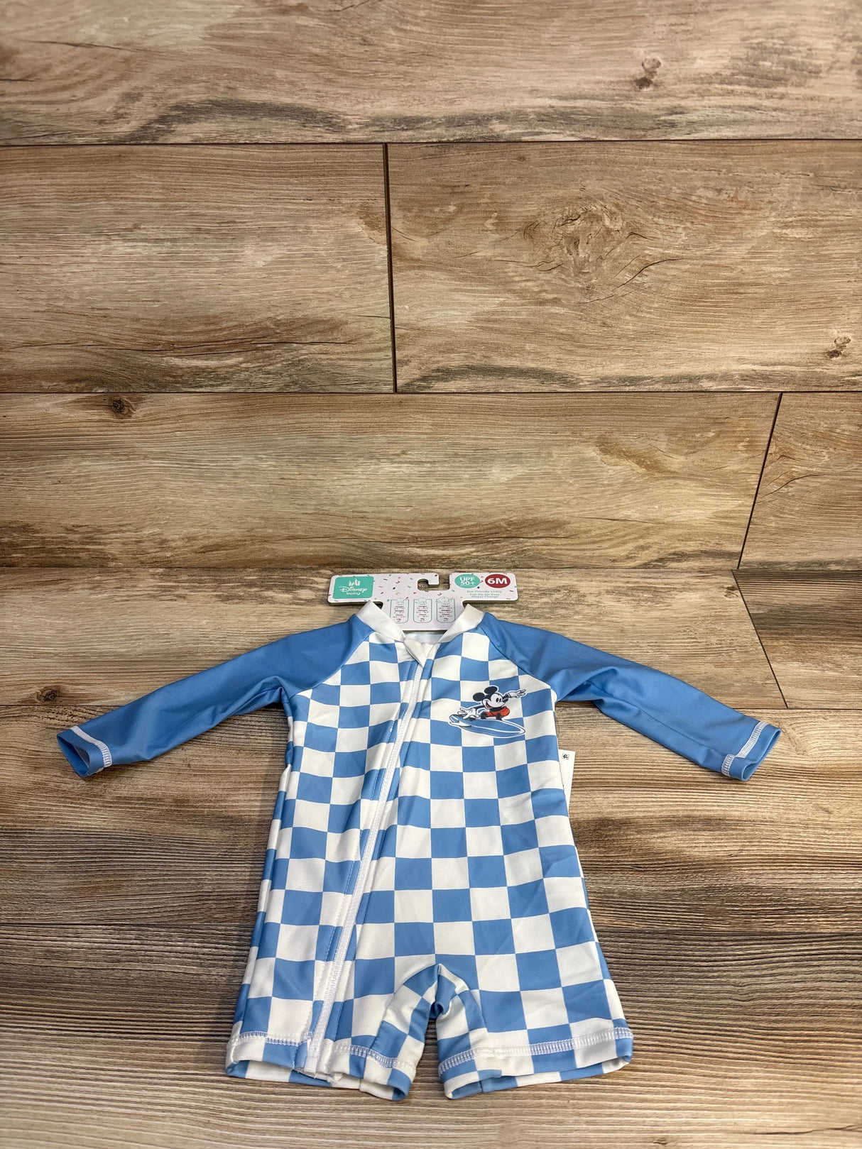 Blue and white checkered baby rash guard with Mickey Mouse, UPF 50+, 6M size, on wood floor