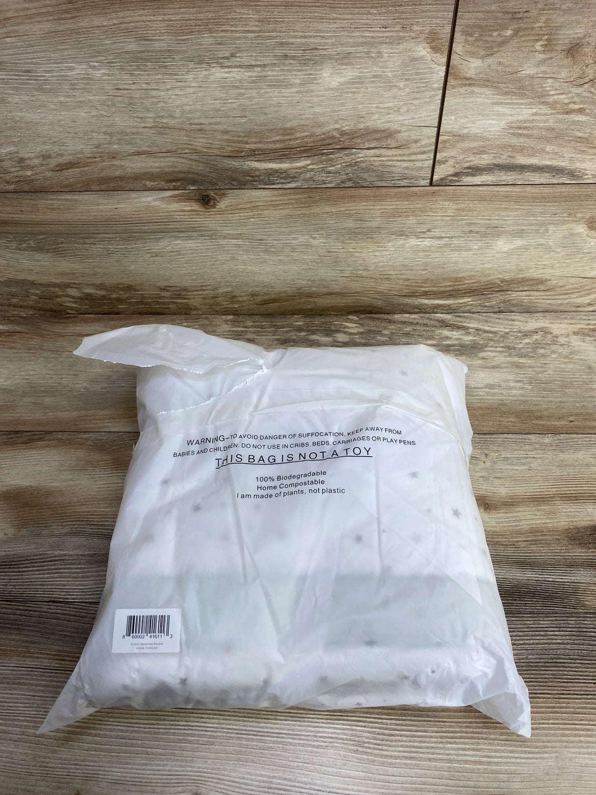 White biodegradable plastic bag with safety warning and barcode on wood floor background