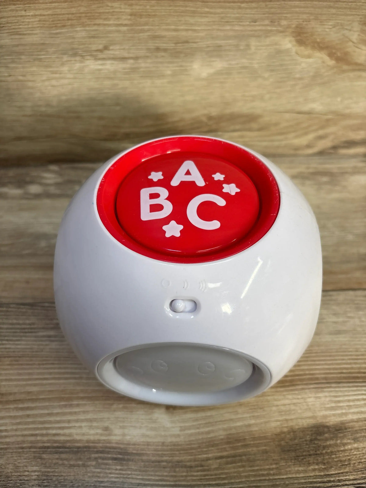 Front view of Best Learning Learning Cube showcasing red ABC panel and volume switch on a wood surface