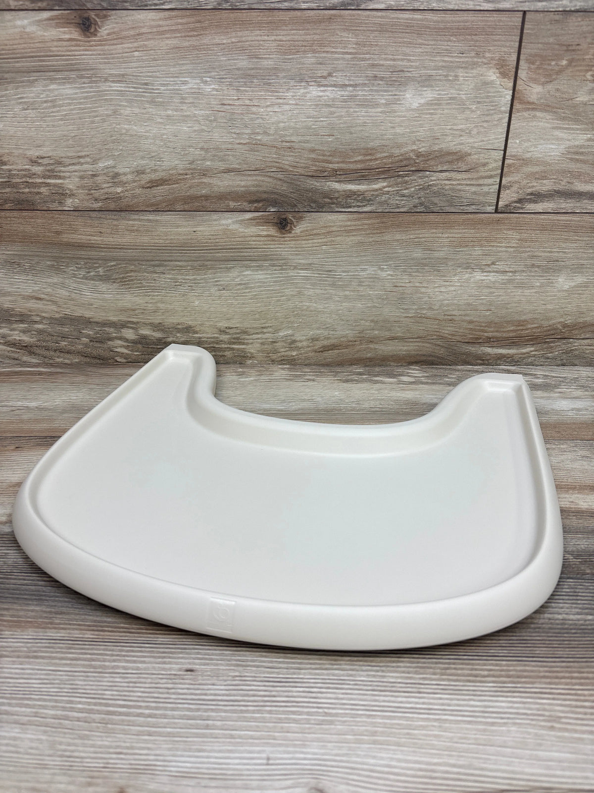 Close-up of the Stokke Tripp Trapp high chair tray showcasing its white molded surface on a wood-look floor