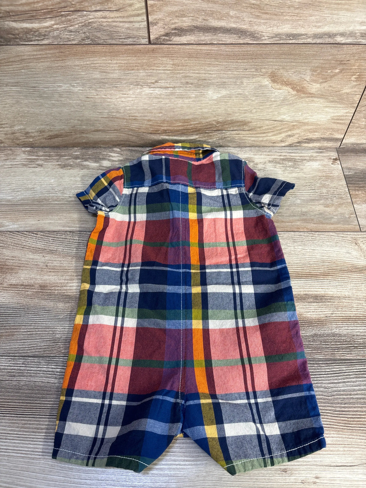 Front view of Baby Gap blue plaid polo romper, size 6 to 12 months, with polo collar, short sleeves, and wood floor background