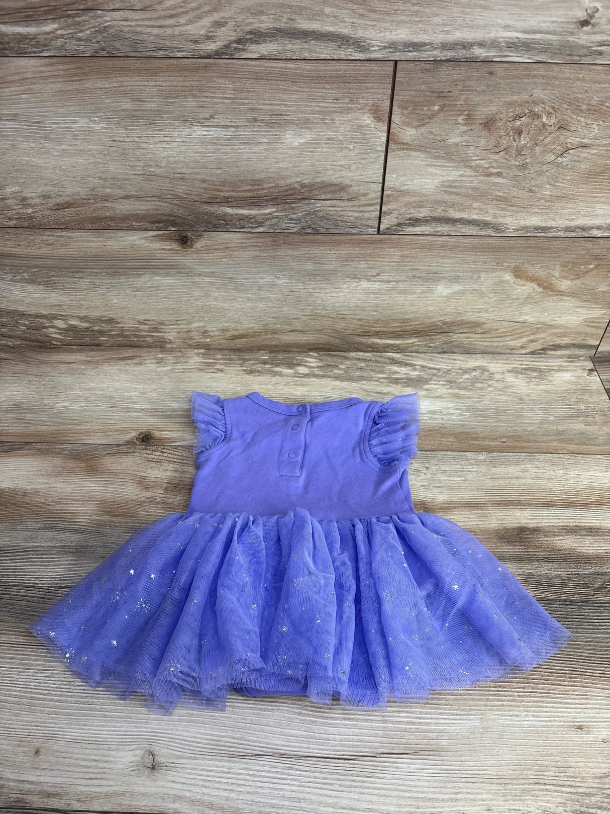 Purple toddler dress with ruffled mesh tutu skirt and silver star details on wood floor