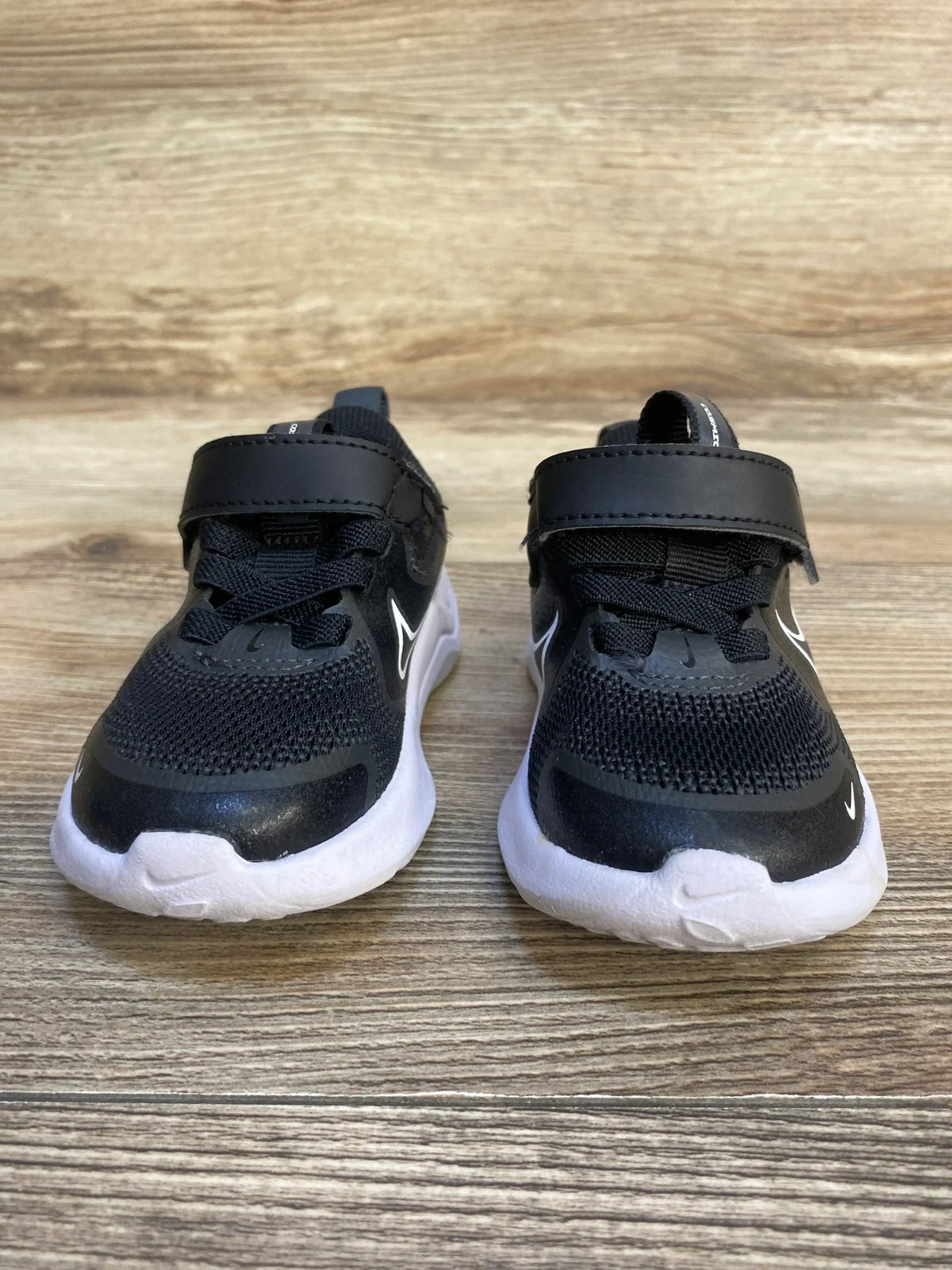Black and white toddler sneakers with velcro straps on wood background