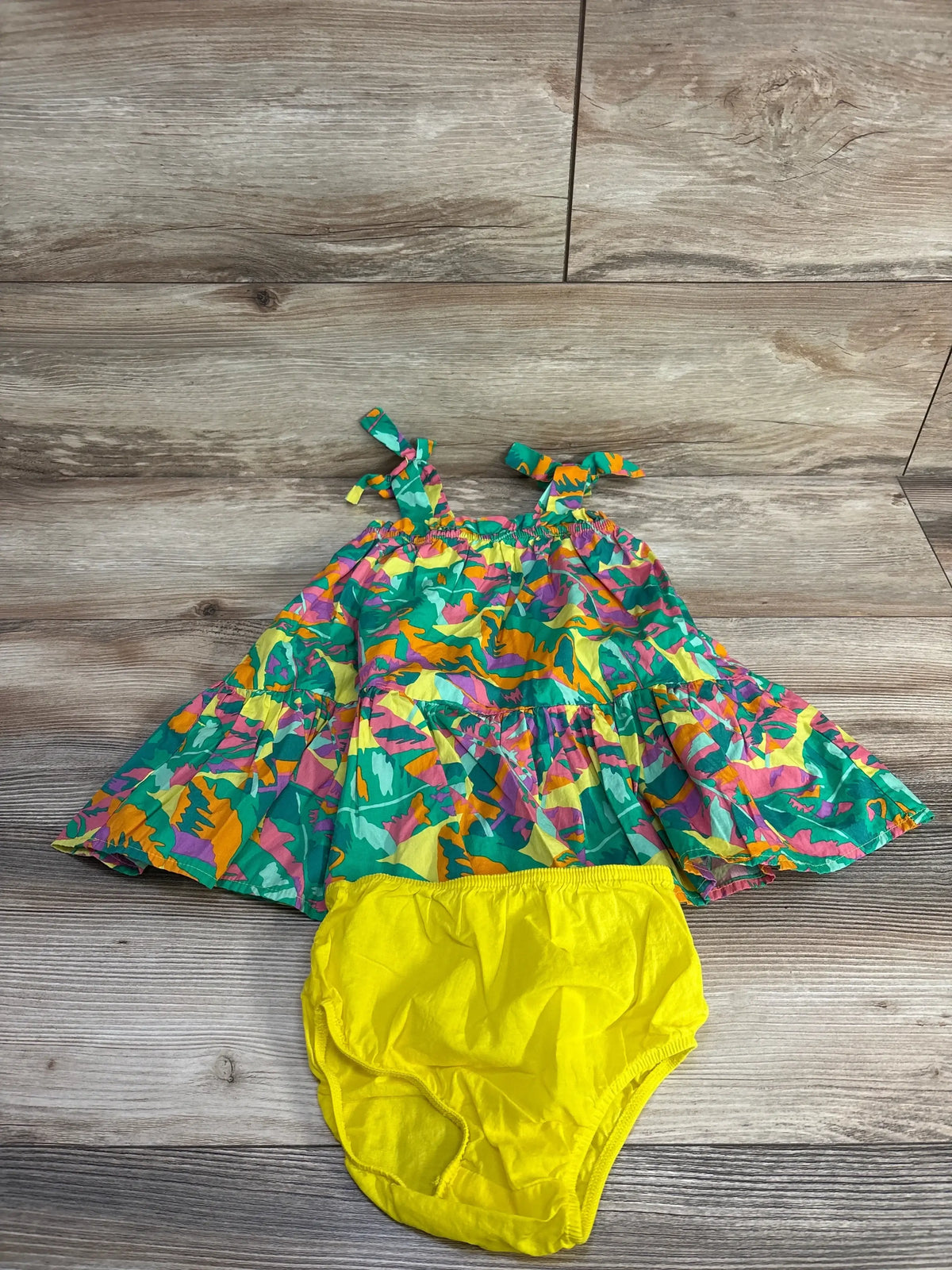Flat lay of Cat & Jack sleeveless multicolored dress with tie shoulder straps and yellow bloomers on wood floor