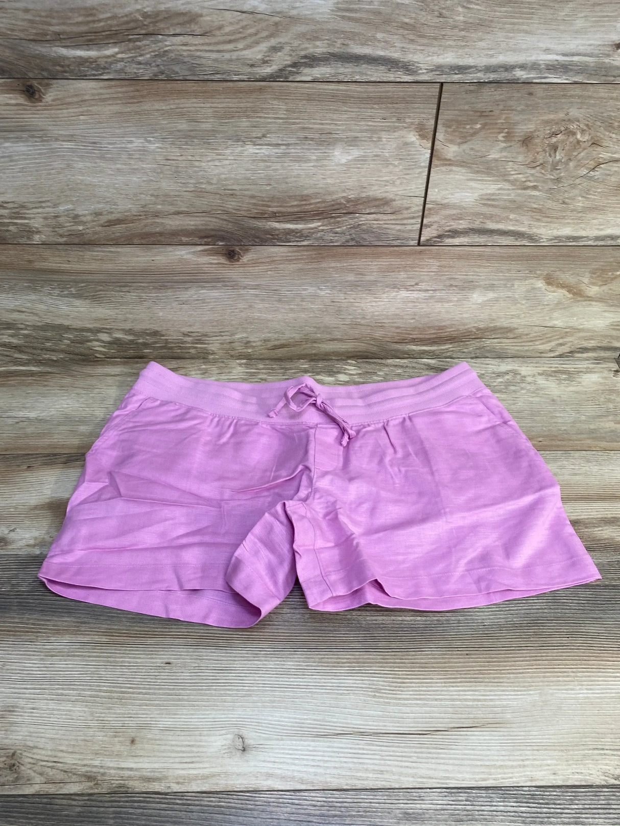 Front flat-lay of Gap maternity linen-cotton pink shorts, size large, showing elastic drawstring waist on wood background