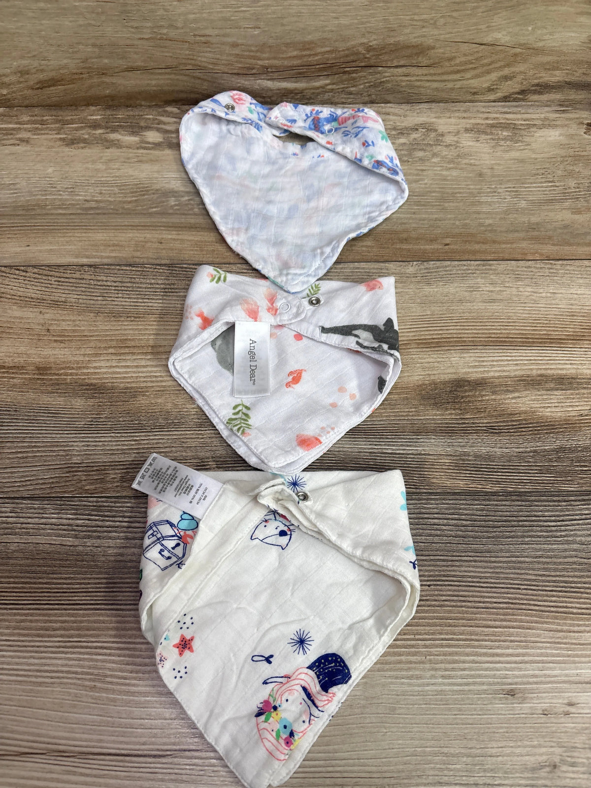 Three white Me n Mommy To Be patterned bandana bibs arranged on a wooden surface.