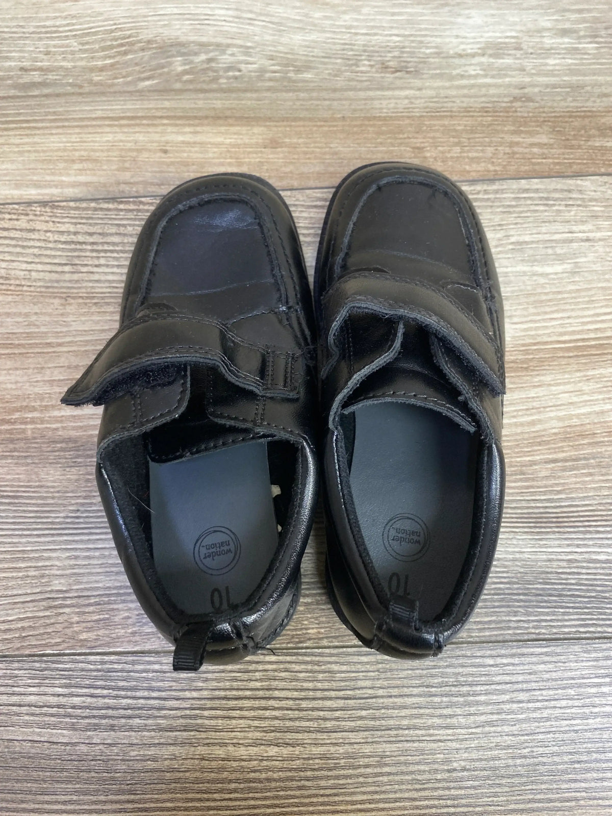 Top view of Wonder Nation Oxford black toddler dress shoes with hook-and-loop straps, size 10 visible, scuffs on wood floor