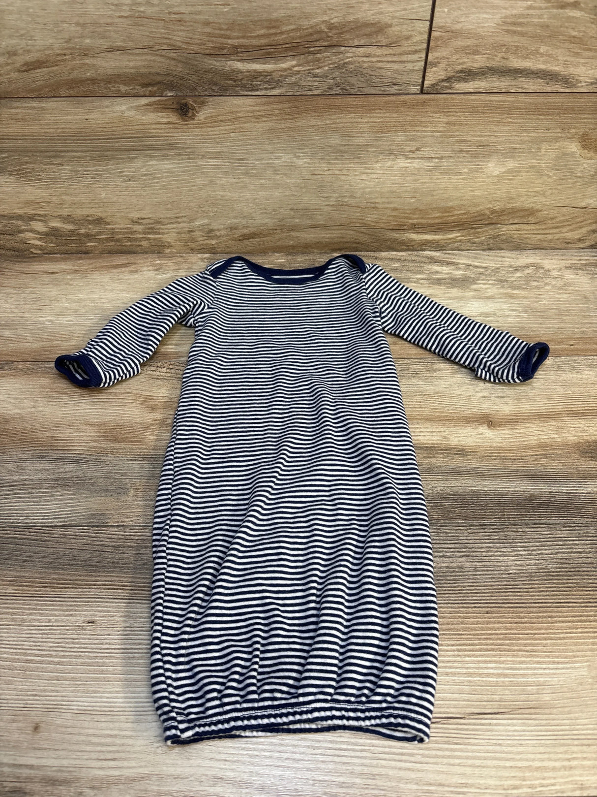 Striped long sleeve baby gown with navy and white pattern on wooden background
