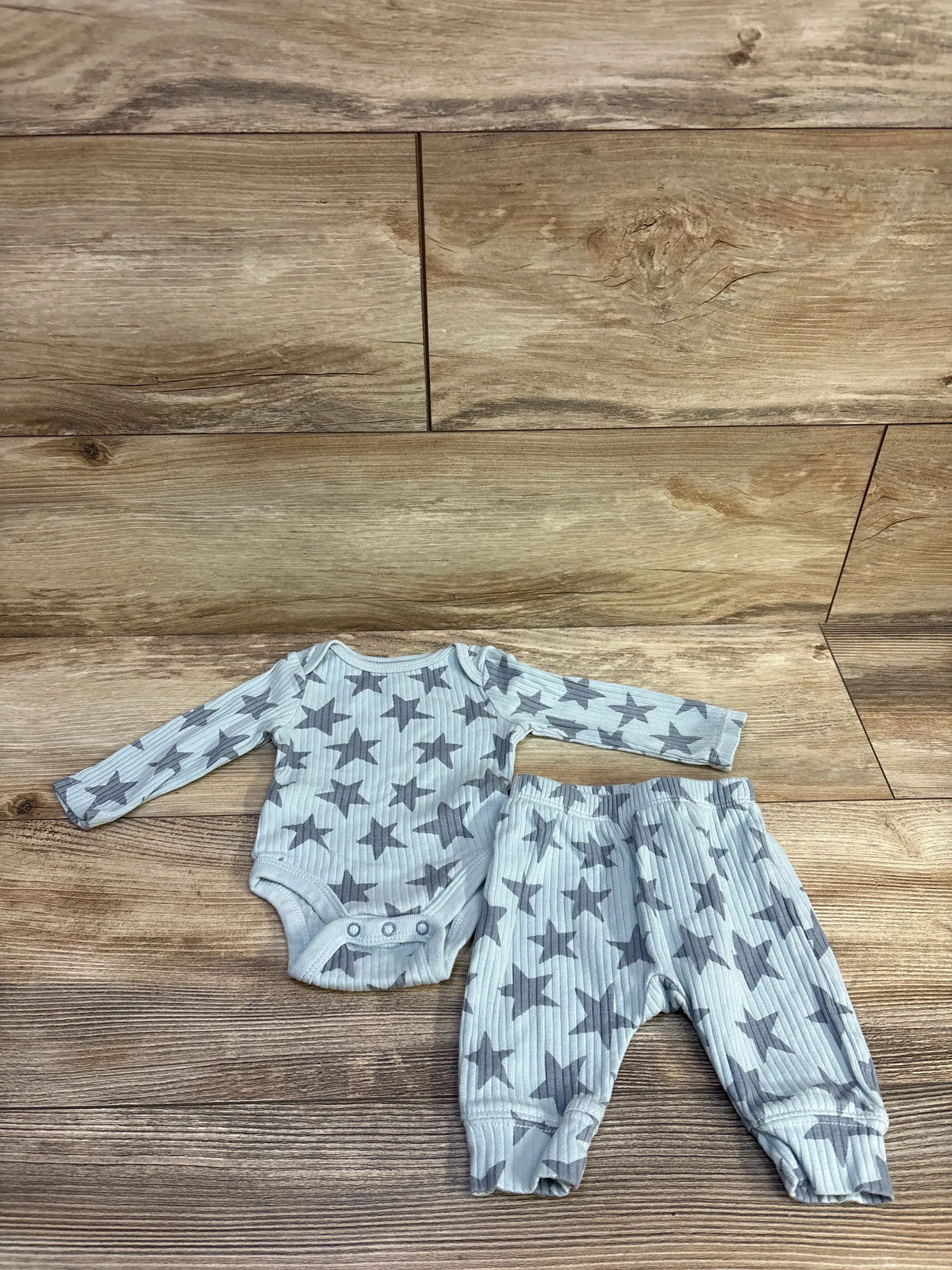 Top view of blue ribbed star-print newborn bodysuit and pants set on a wood-look surface