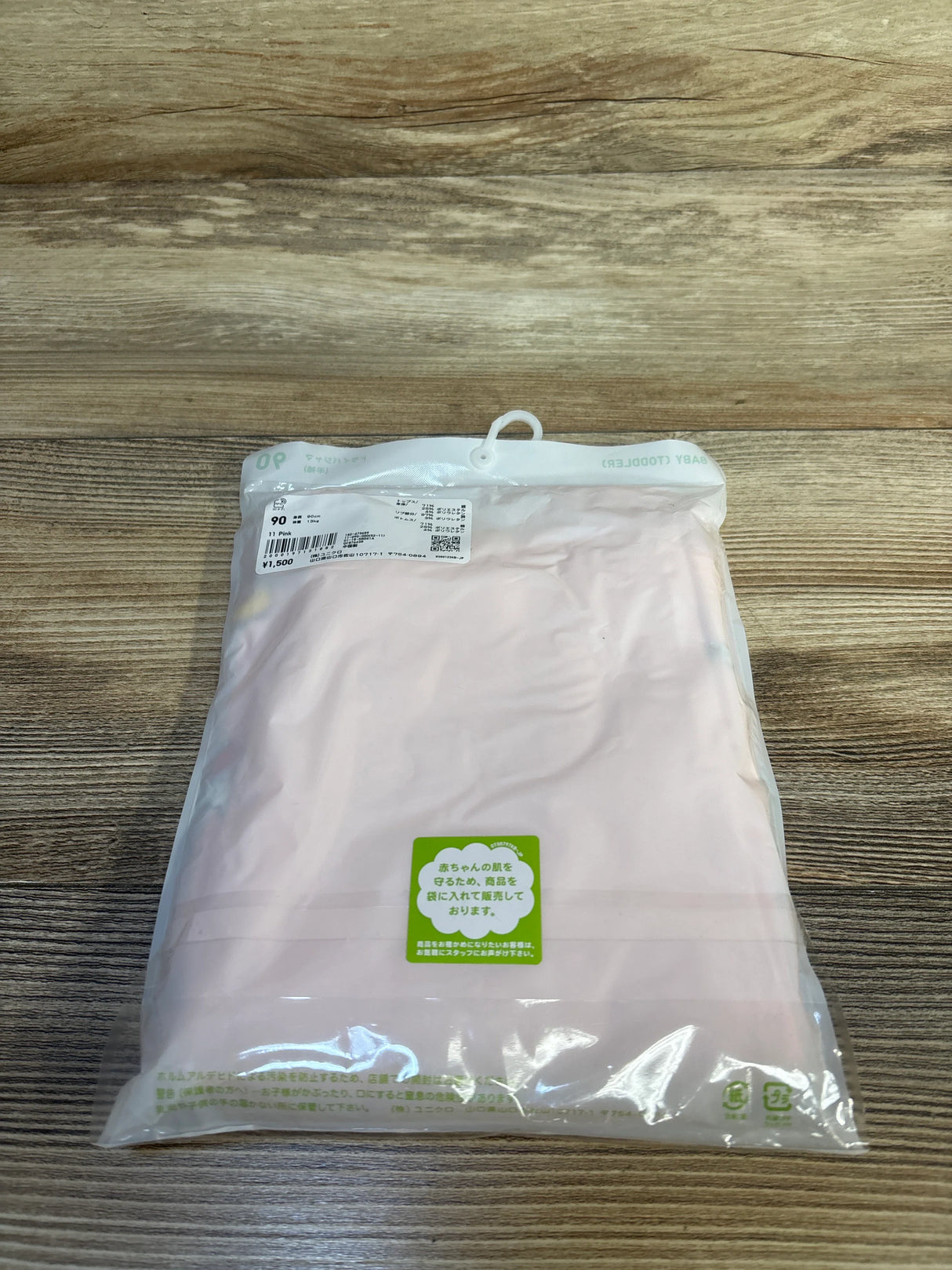 Folded pink Uniqlo Miffy 2-piece toddler pajama set in clear retail packaging showing size 90 label on wood surface
