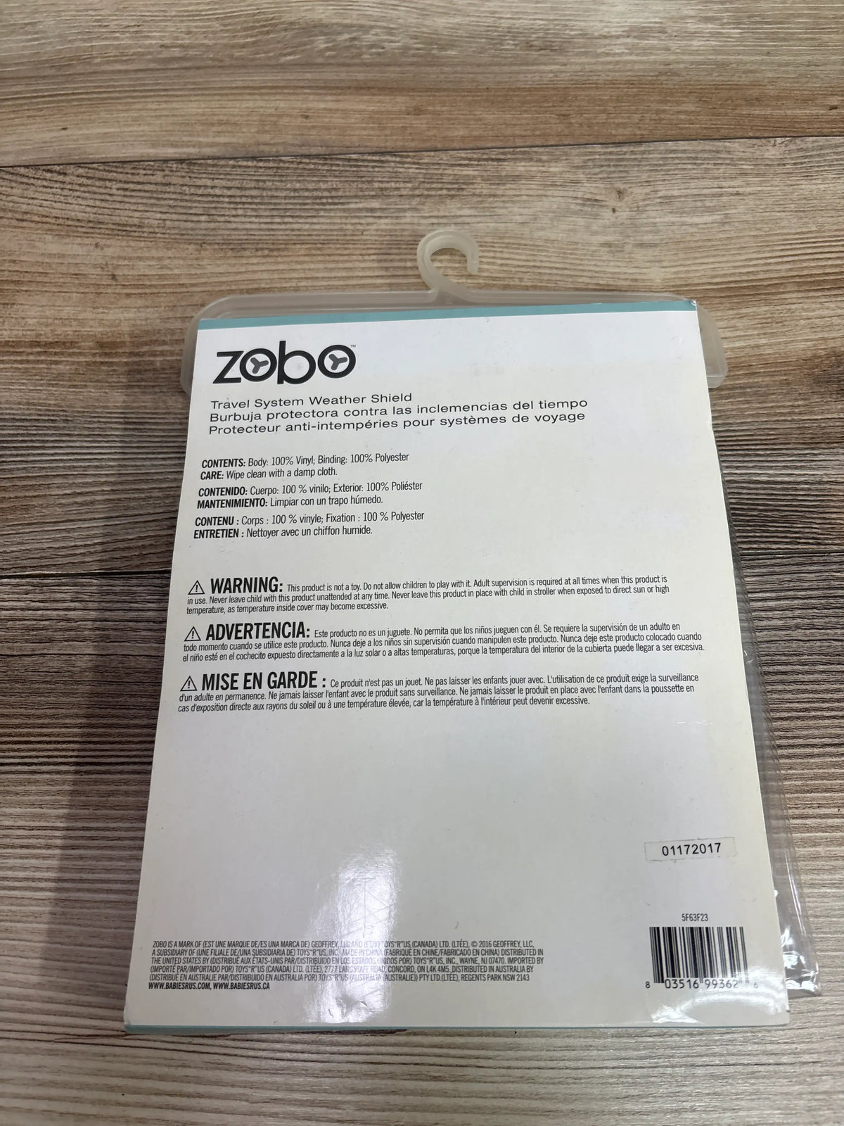 Front view of Zobo travel system weather shield package showcasing vinyl body and polyester binding on a wood surface