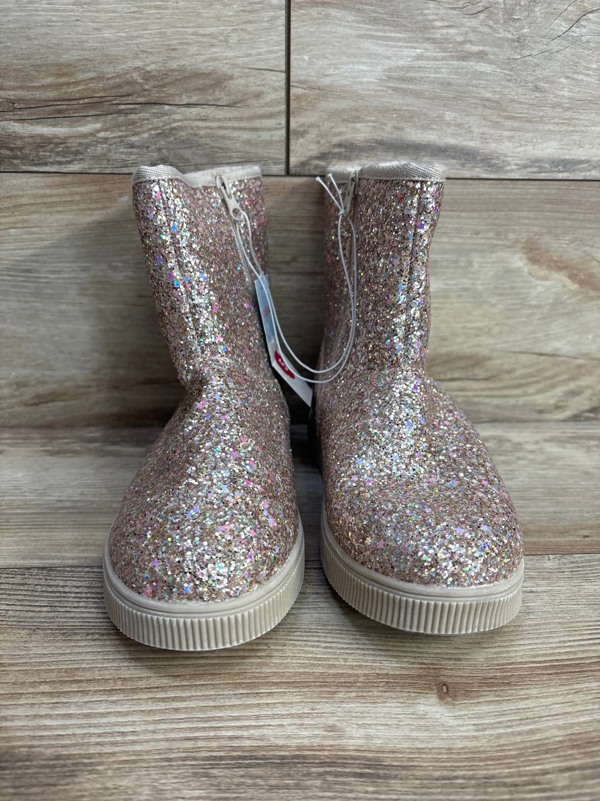 Sparkly pink glitter kids boots with rubber soles on wood background