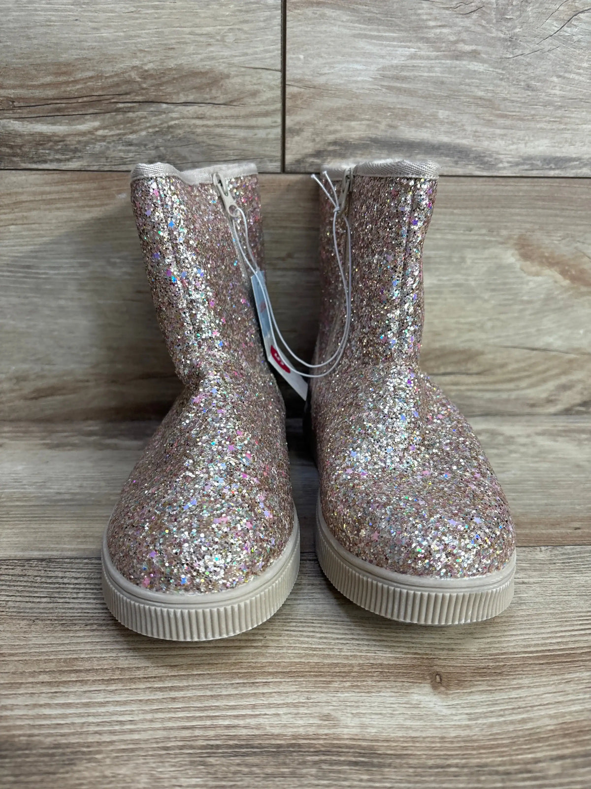 Front view of Cat & Jack Holland shearling-style kids boots in glittery gold showing glitter upper, side zipper, and rubber sole on wood background