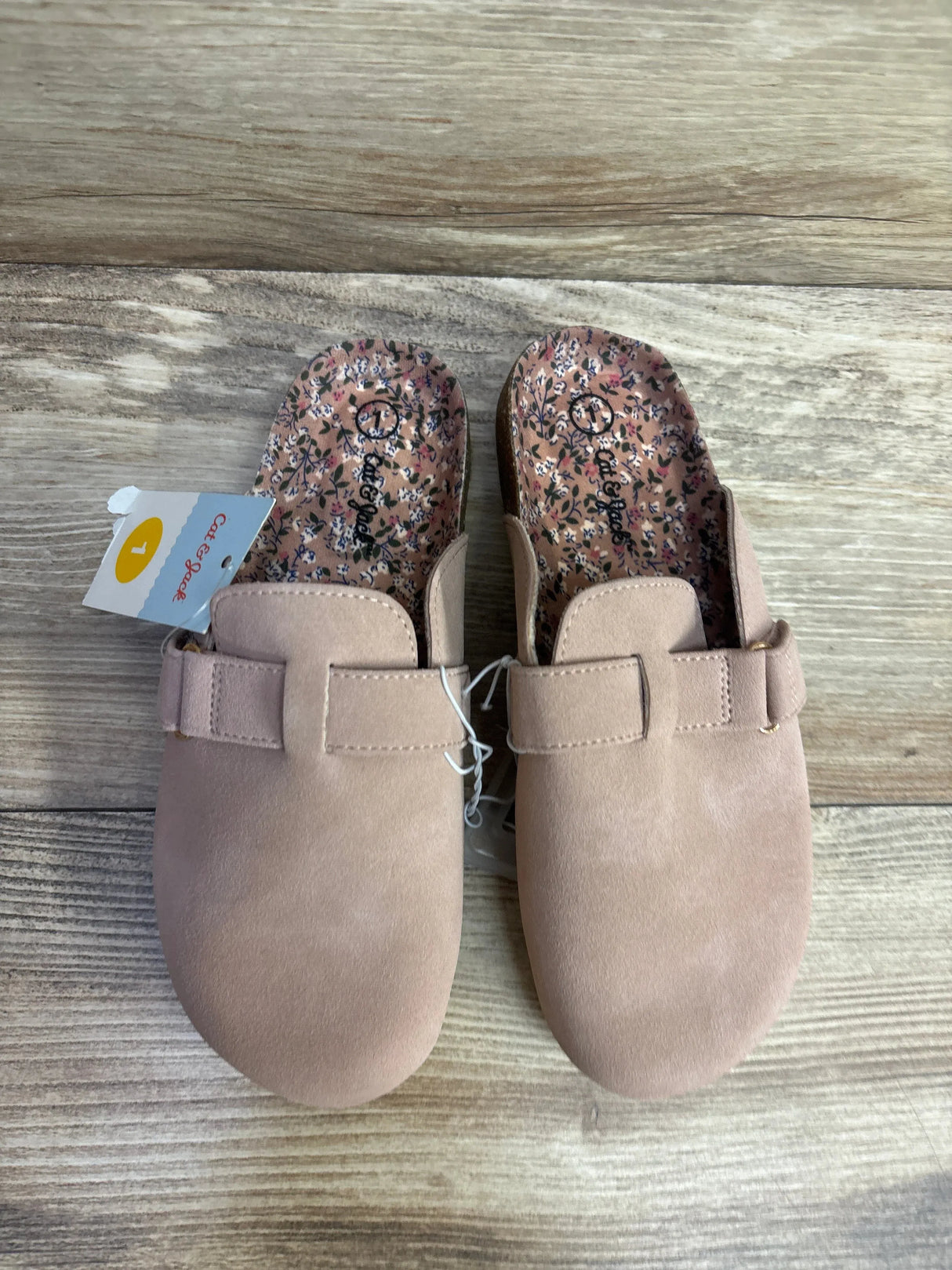 Pair of pink Cat & Jack slip-on clogs with floral insoles on wooden floor