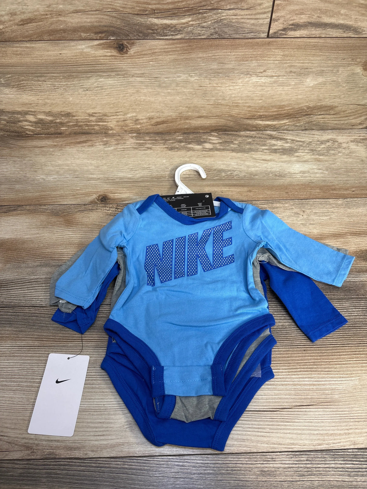 Nike baby blue long sleeve onesies set with logo on wood background