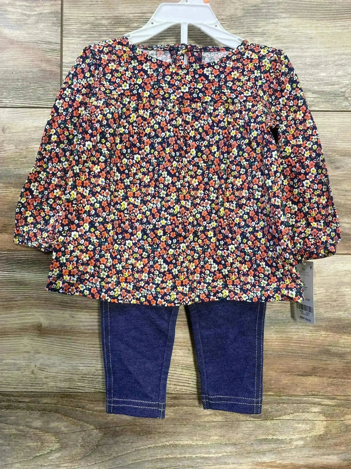 Front view of Carter’s navy 2-piece floral top and leggings showcasing all-over small orange and yellow flower print with wooden background