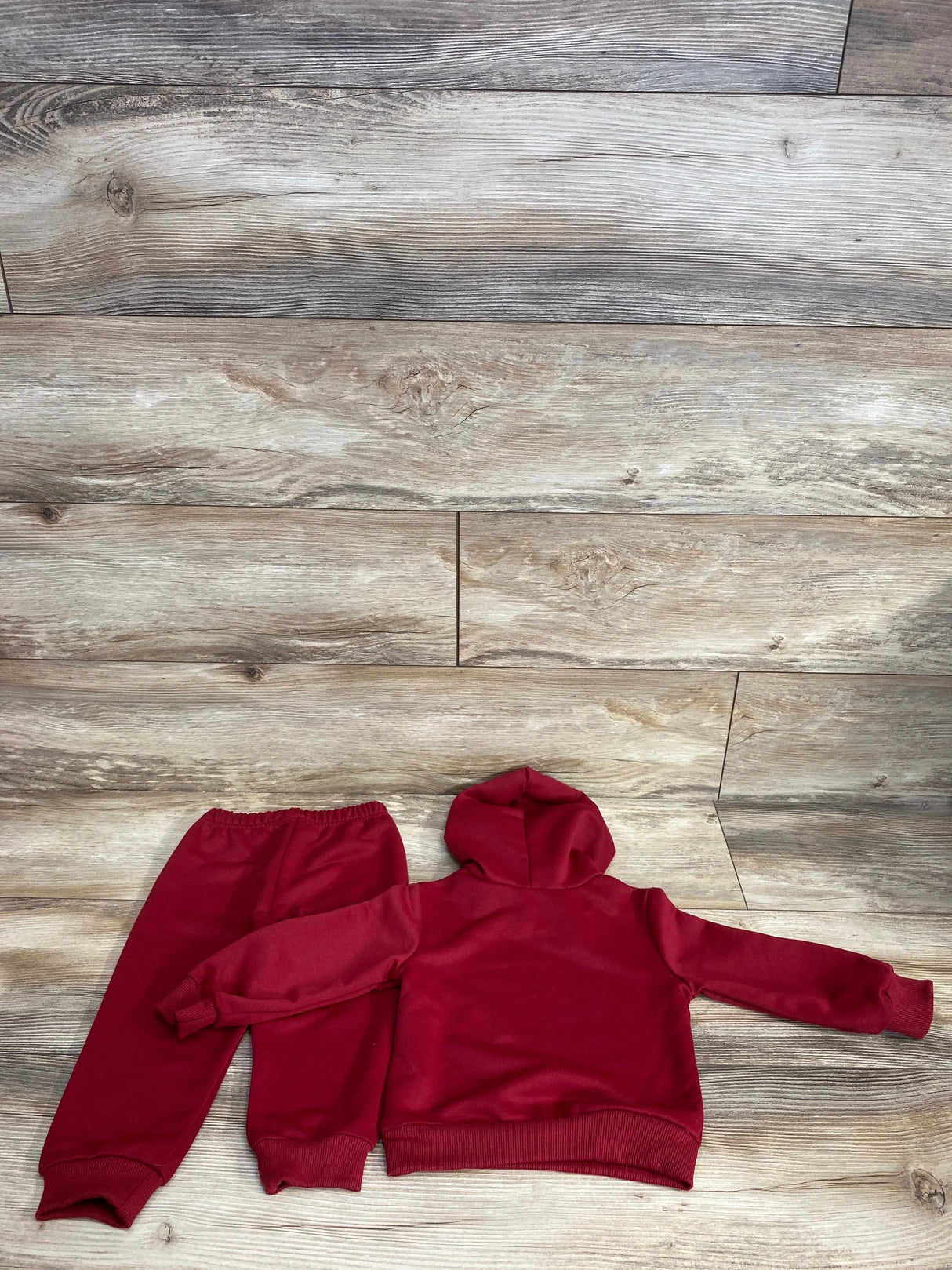 Children's red hooded sweatshirt and elastic waist pants set displayed on wood floor