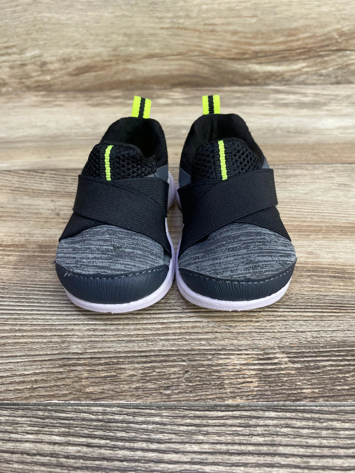 Front view of Wonder Nation Casual Slip-On sneakers size 2C showcasing gray knit toe, black elastic cross straps and neon yellow pull tabs on wood floor