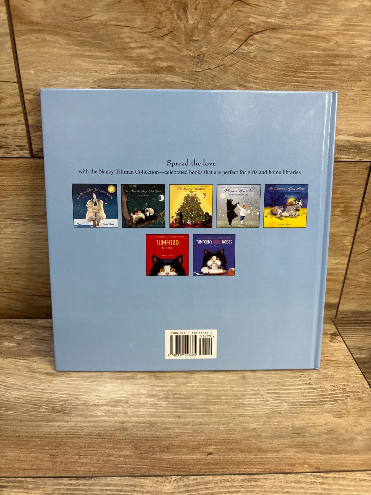 Back view of I’d Know You Anywhere, My Love hardcover showing light blue back with small thumbnails and barcode on wooden table