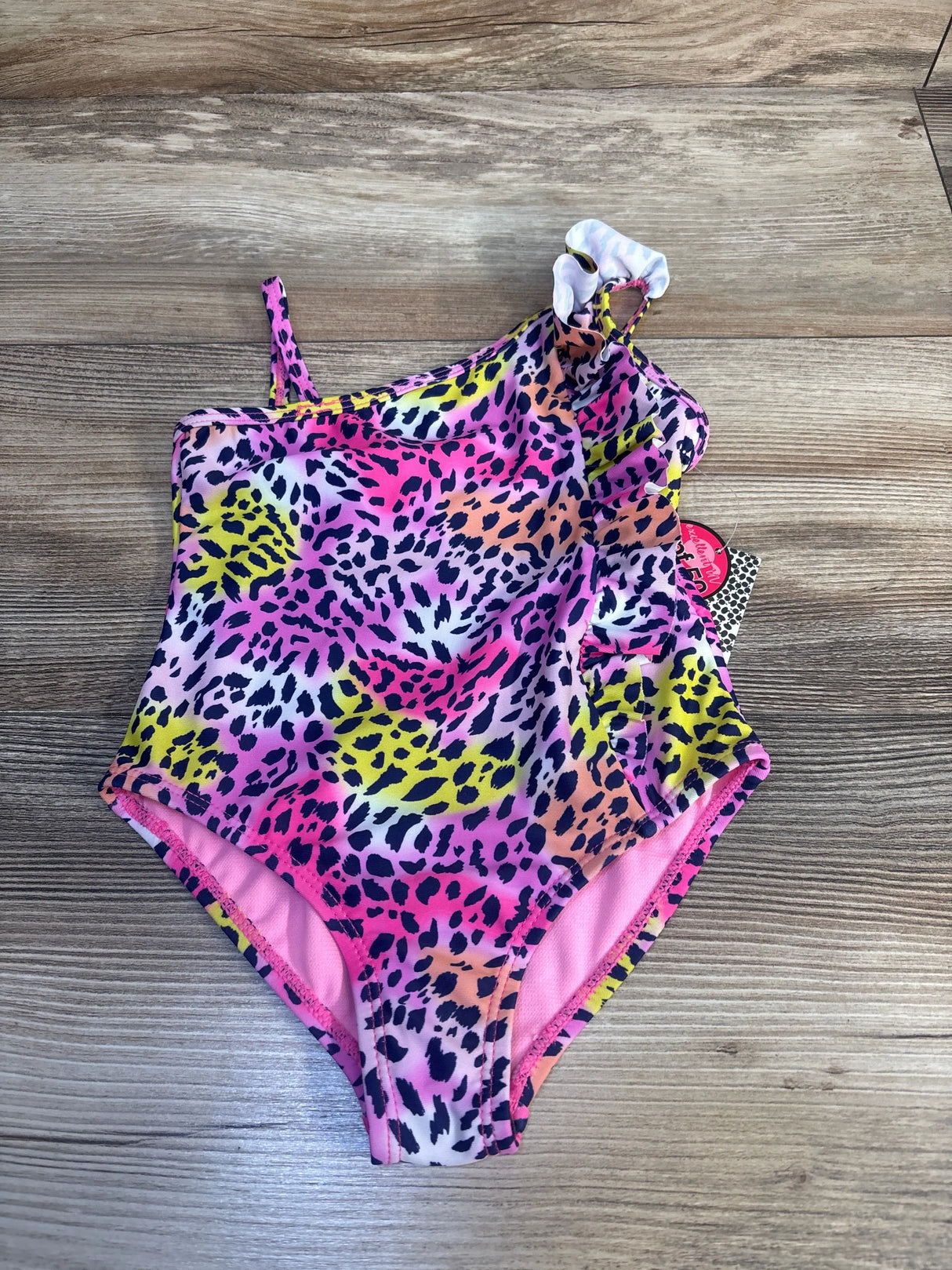 Colorful girls one-shoulder leopard print swimsuit with ruffle detail on wood background