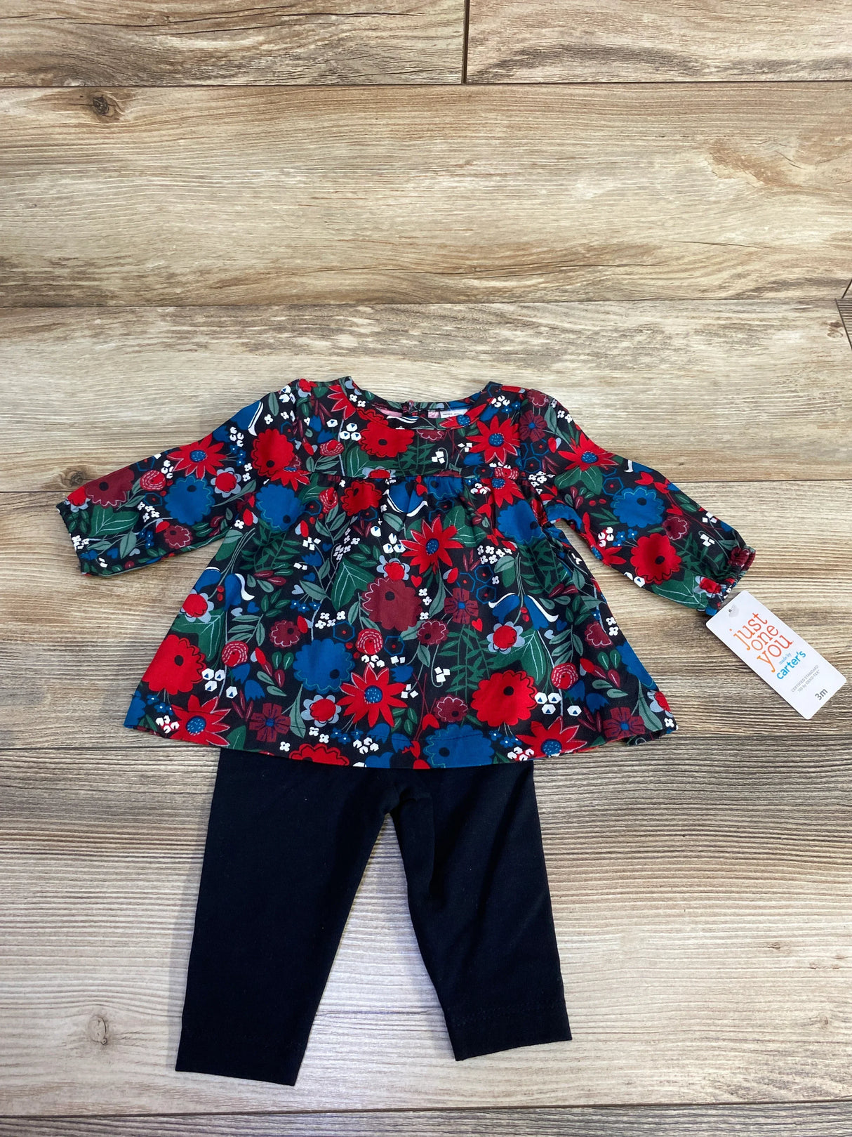 Baby girl's floral long-sleeve dress with colorful red and blue flowers and black leggings set on wooden floor