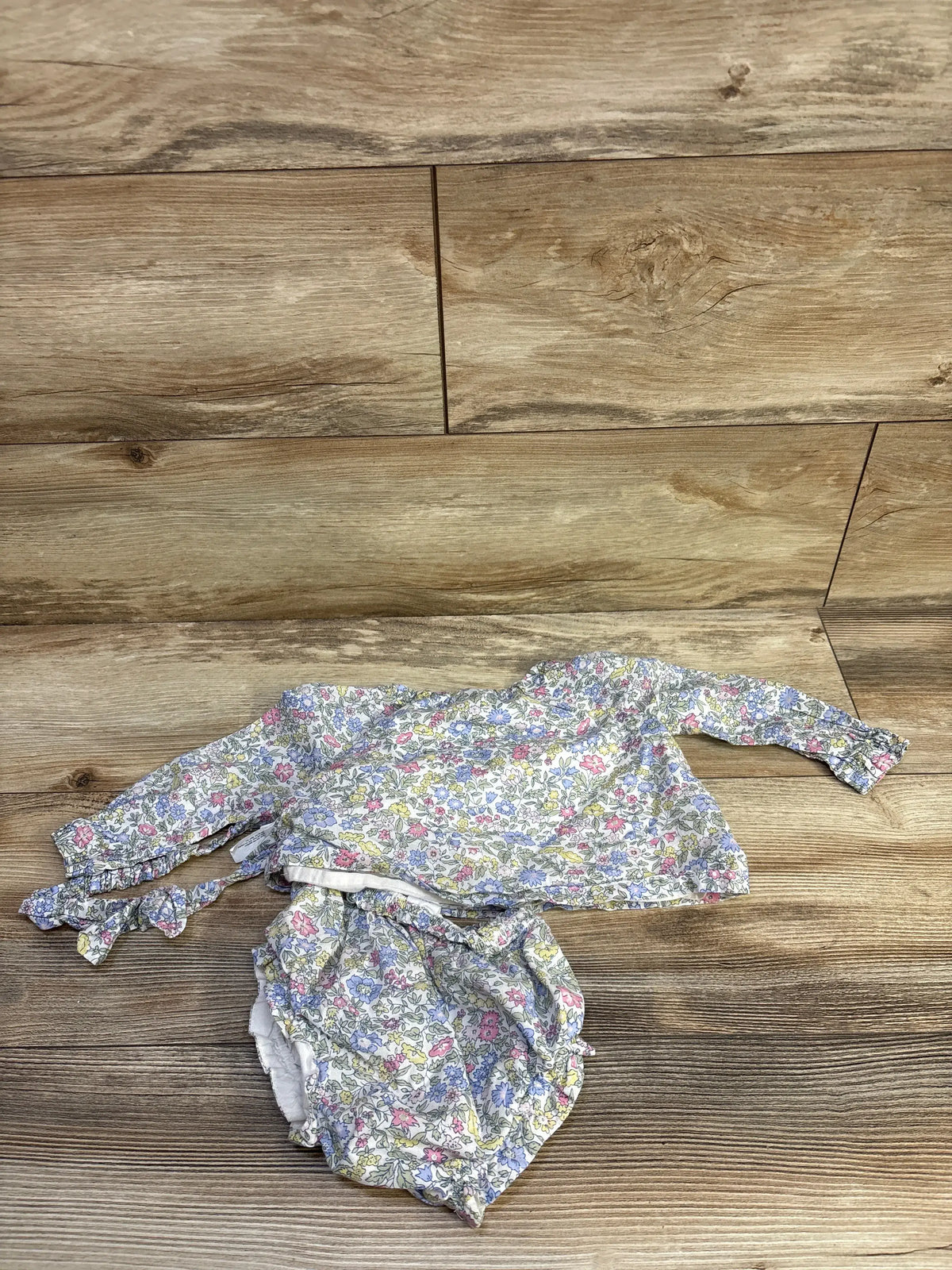 Flat lay of Baby Gap floral three-piece set showcasing long sleeve top, bloomers, and headband on wood background